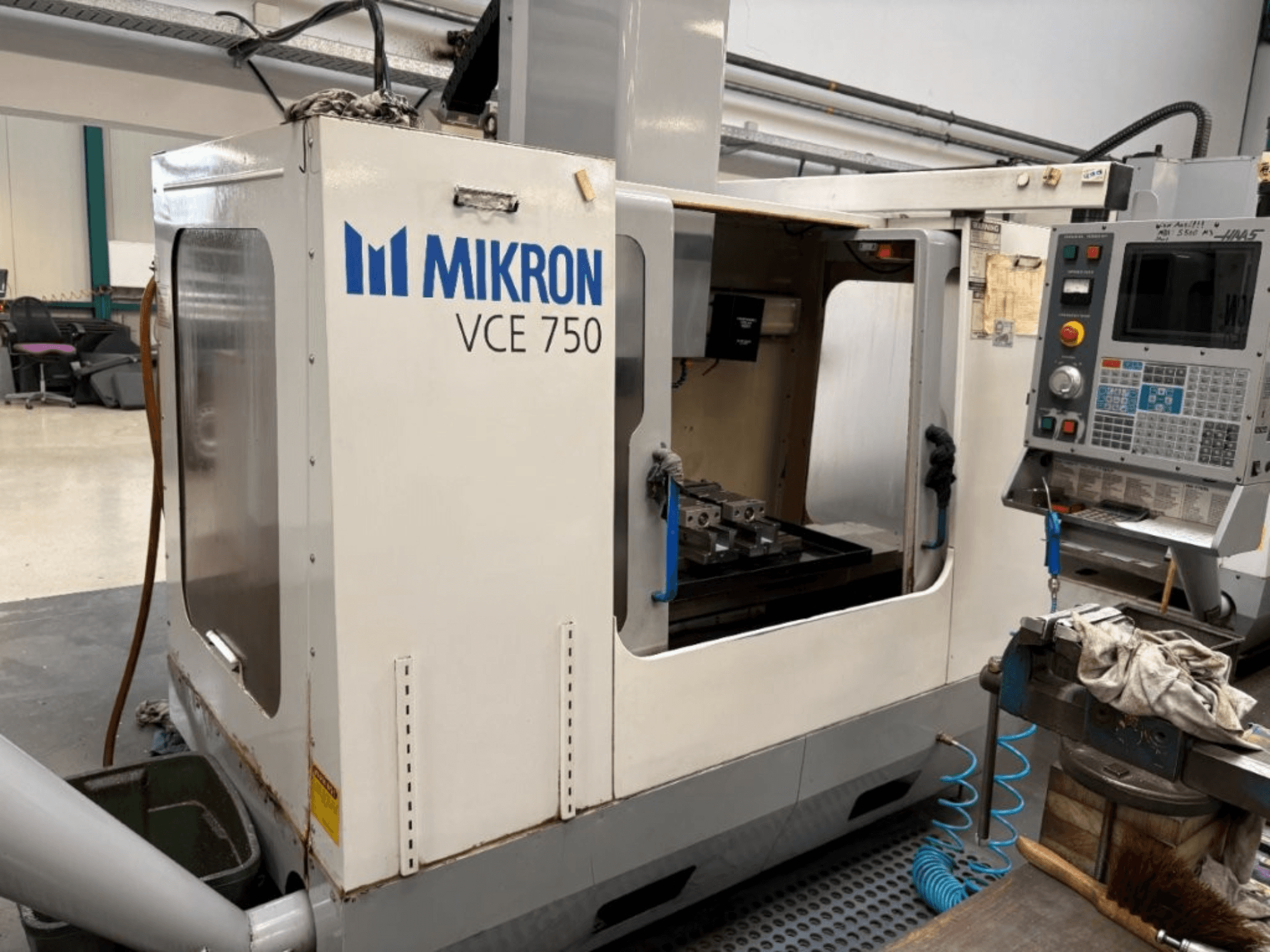 Mikron VCE 750 CNC-freespingi esivaade, millel on töödeldud töölaud ja juhtpaneel erinevate nuppude ja ekraanidega.