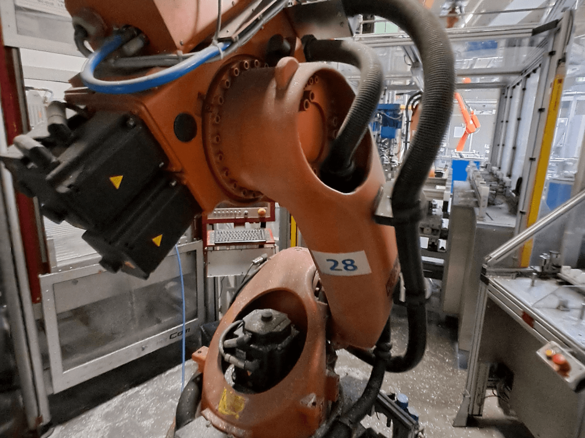 KUKA KR30-3 robotkäe lähivõte: oranž korpus, millel on number 28, ning külgvaates on näha mootorid ja juhtmestik.