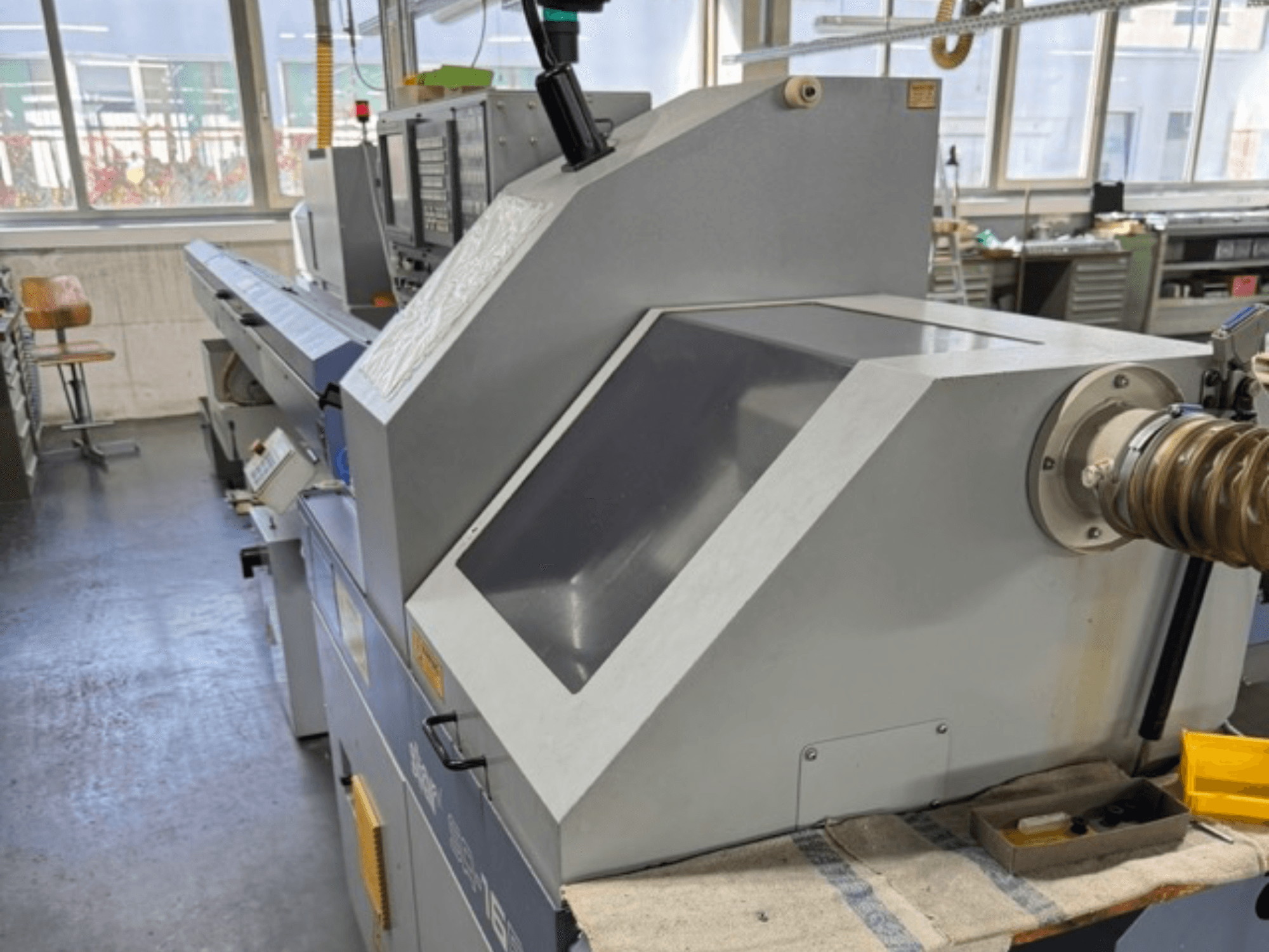 Küljelt vaadatuna hall tööstuslik masin, millel on suur nurgapealne paneel, juhtnupud ja voolikukinnitus.