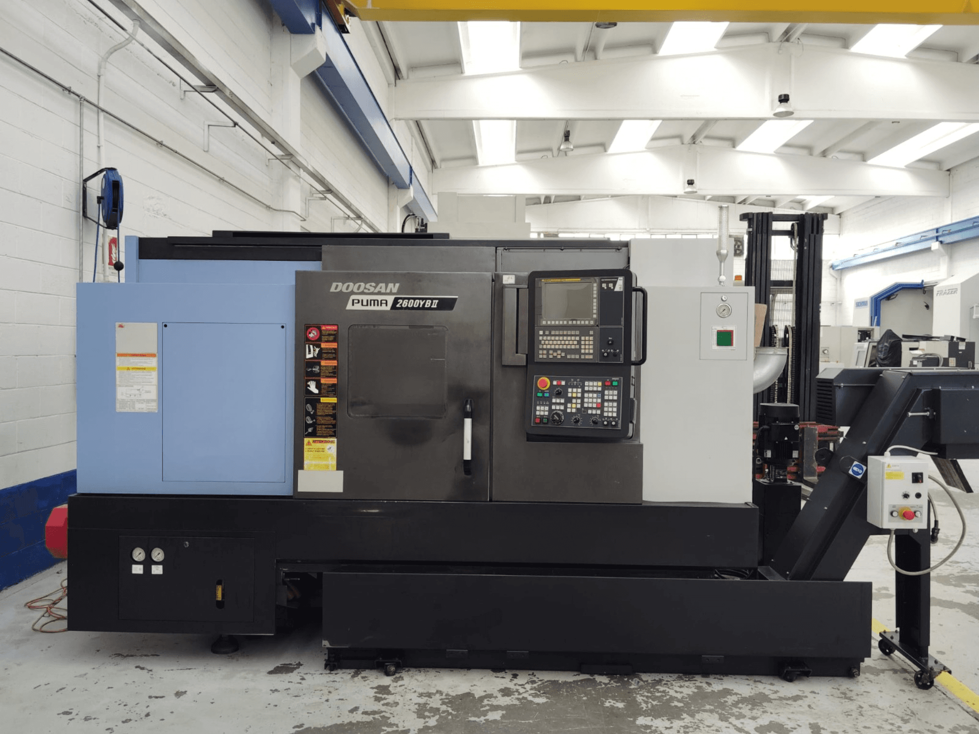 DOOSAN Puma 2600YB II horisontaalse treipingi esivaade koos juhtpaneeli ja ohutussiltidega.