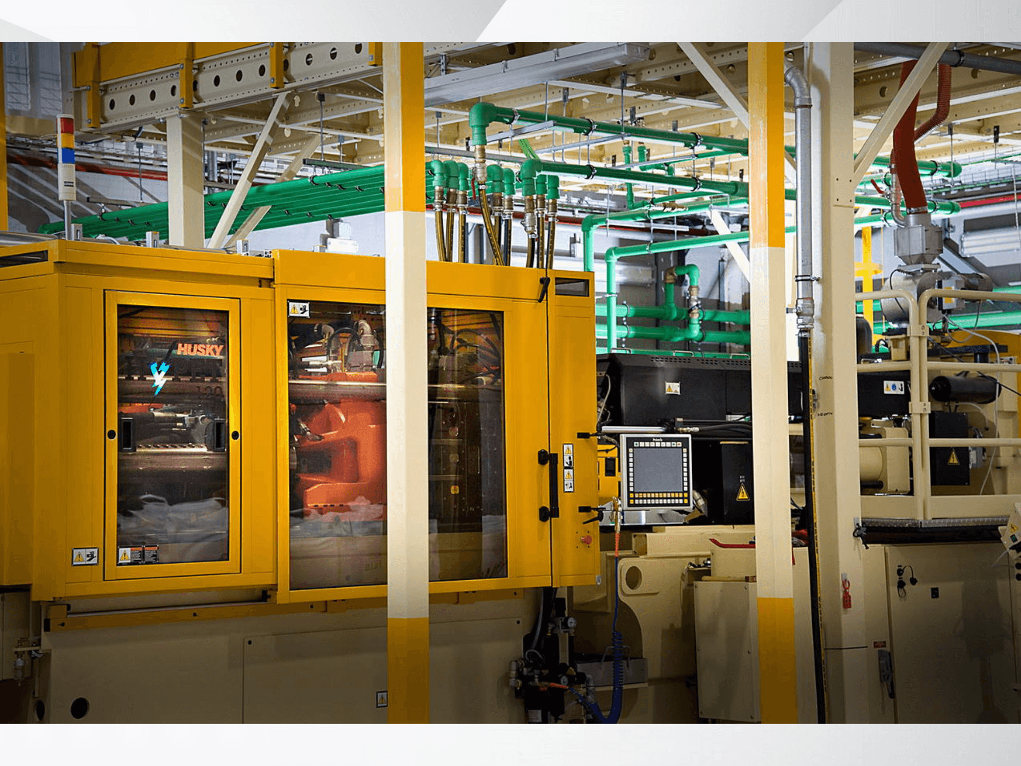 Husky tööstuslik masin kollases toonis, esiplaanil on juhtpaneel ja sisemised mehhanismid tehase taustal.