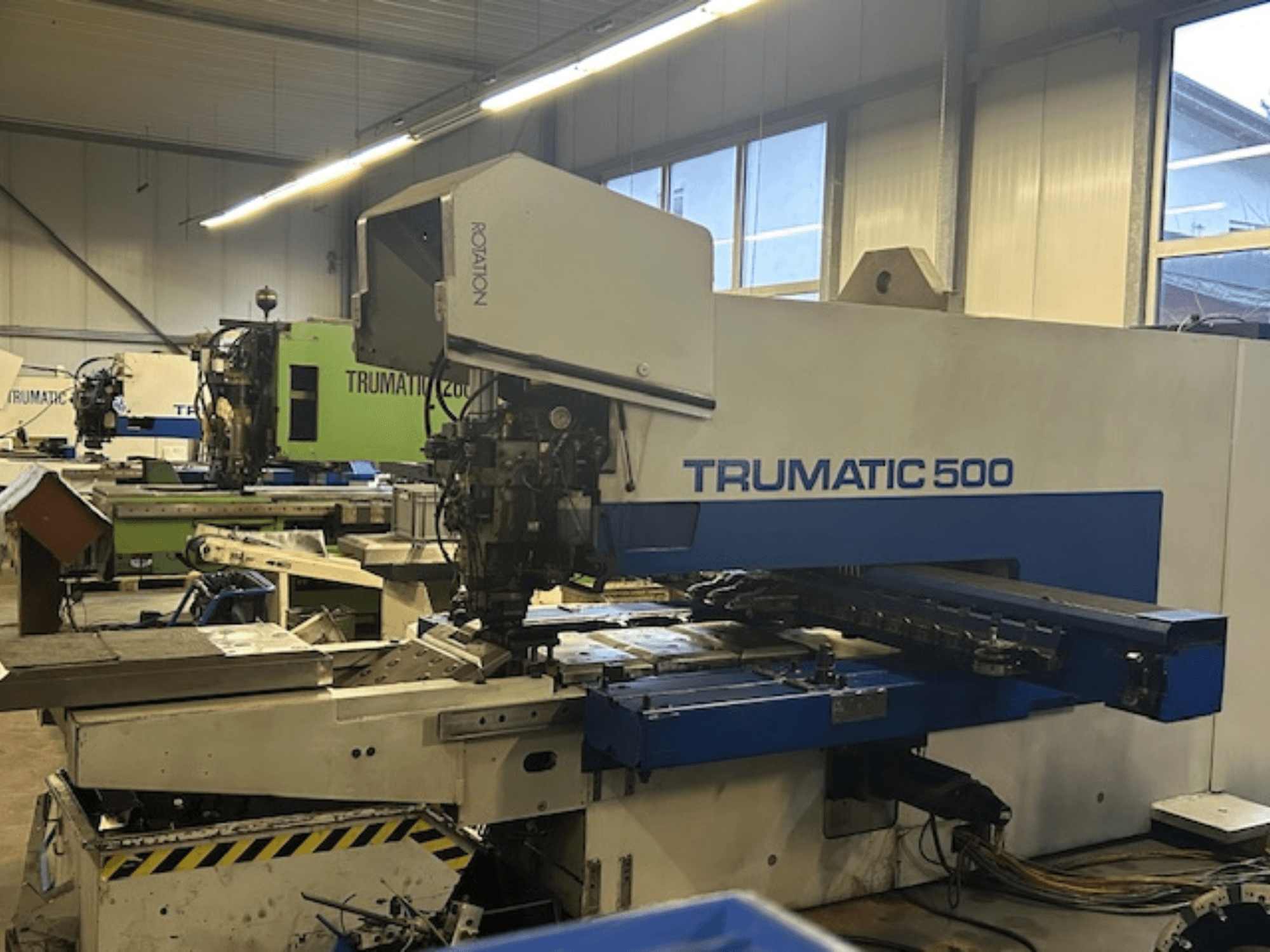 TRUMPF TRUMATIC 500 CNC-stantsimismasin, esiplaanil, juhtpaneel ja mehaanilised osad. Tööstuslik töökoja seade.