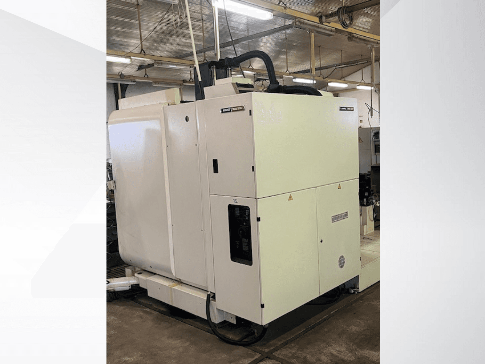 Valge tööstuslik CNC-tööpink ees, millel on juhtpaneel ja ventilatsioon, töökojas.