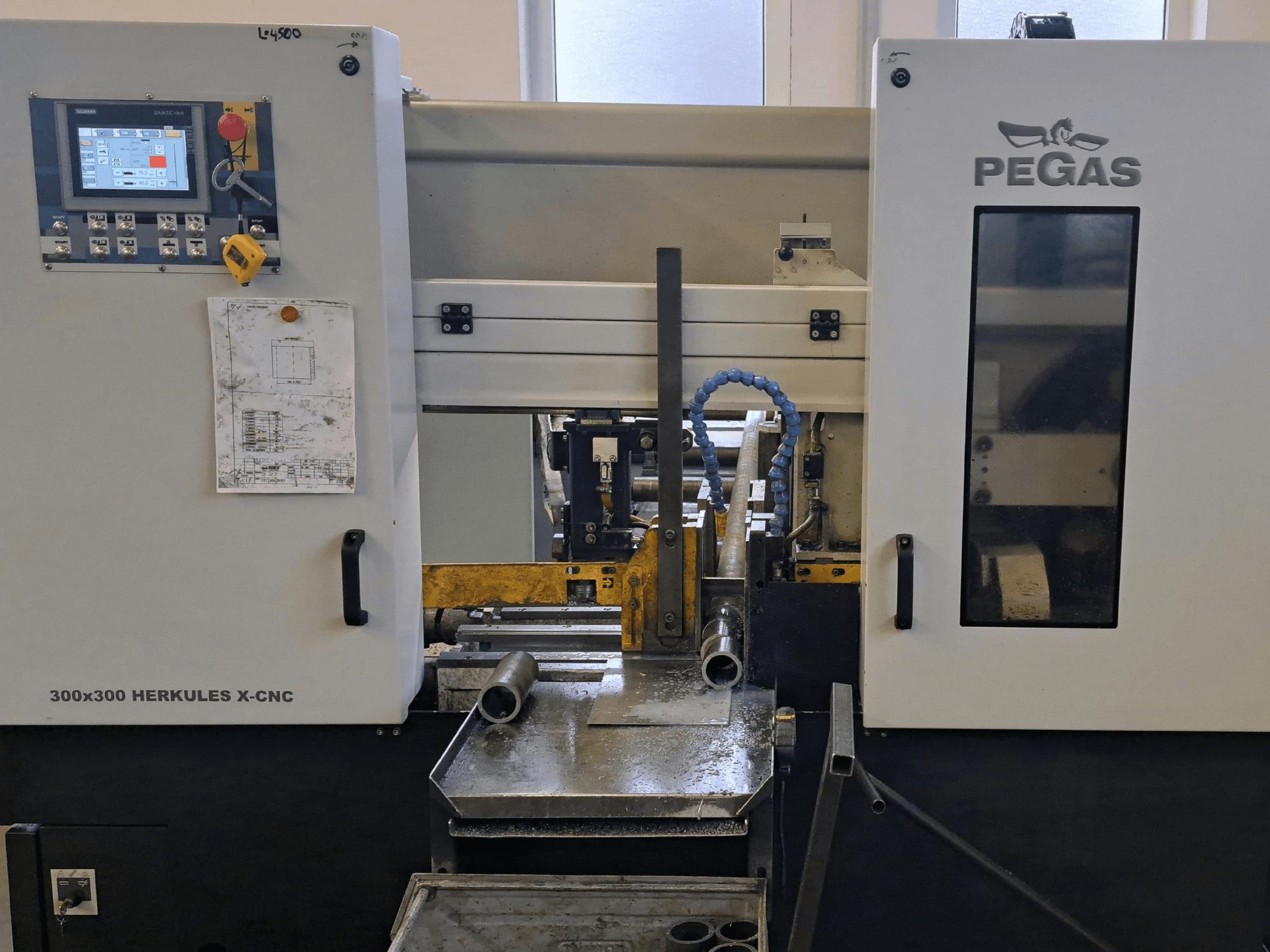 Pegas HERKULES X-CNC 300x300 lehtmetalli töötlemismasin, vaade eest, millel on näha juhtpaneel ja töötsoon koos metallitükkidega.
