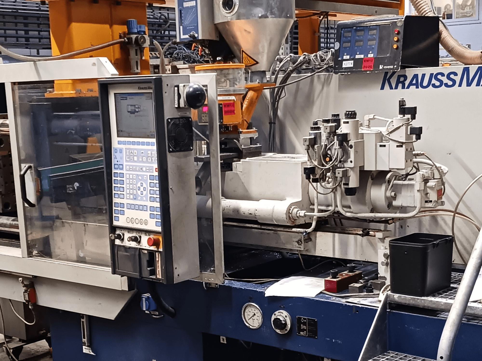 KraussMaffei survevalu masin koos juhtpaneeli, hüdraulikaseadmete ja tööriistadega esiplaanil, esiplaanil.