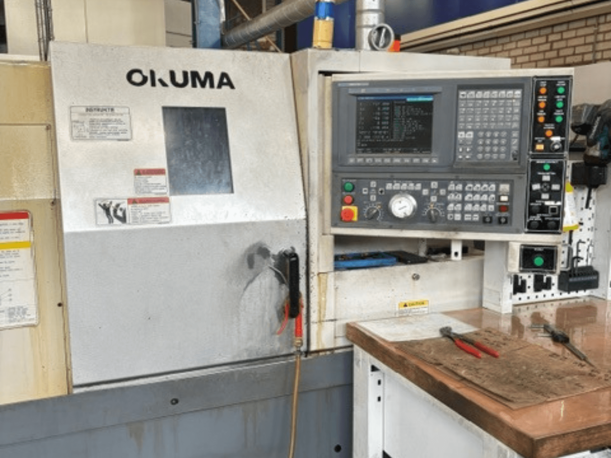 Okuma ES-L10II horisontaalse treipingi vaade eest, millel on näha juhtpaneel, ekraan ja tööala koos tööriistadega.