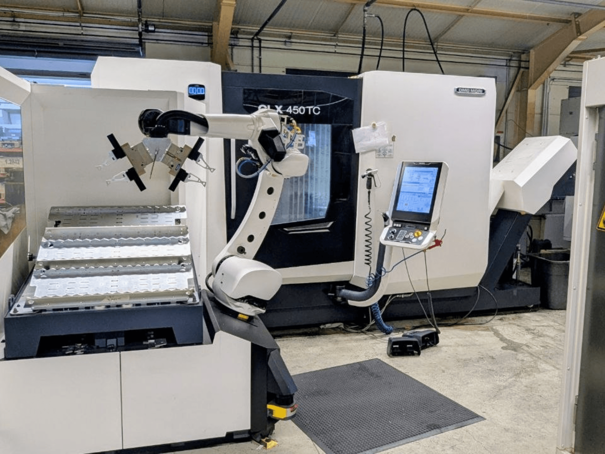 DMG MORI CLX 450 TC koos Robo2go-ga, vaade eest, millel on näha robotkäsi ja juhtpaneel masina kõrval.