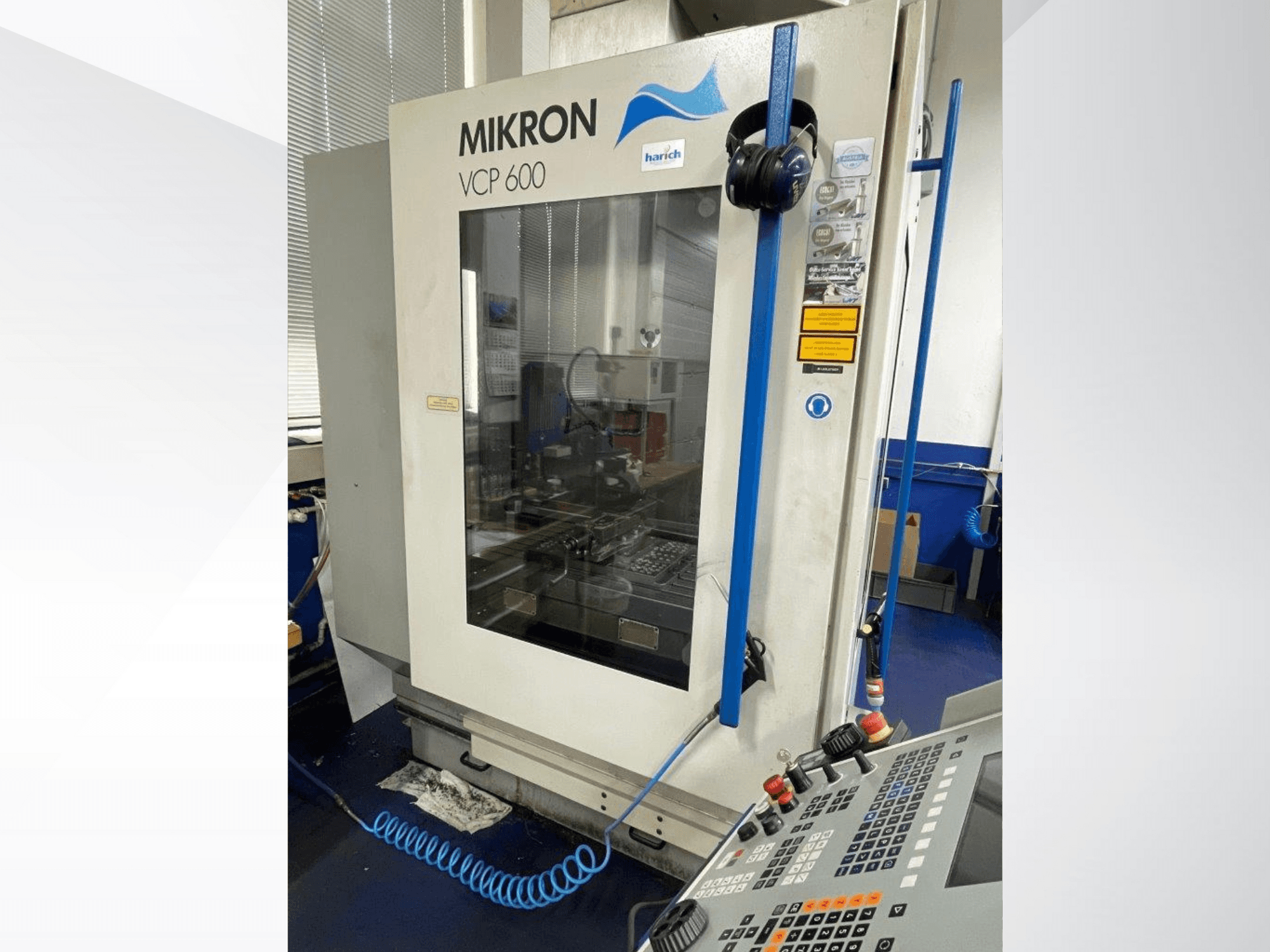 Mikron VCP 600 CNC-tööpink, esiplaan, juhtpaneel koos nuppudega ja nähtav töötlemisala klaasi taga.
