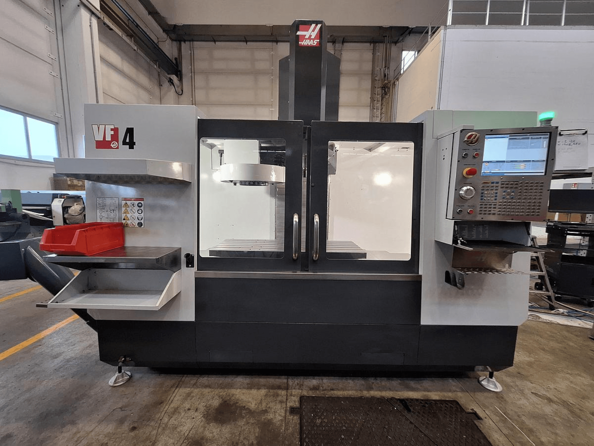 Haas VF-4 vertikaalne töötluskeskus, esivaade, kus on juhtpaneel, tööriistahoidja ja avar tööala.