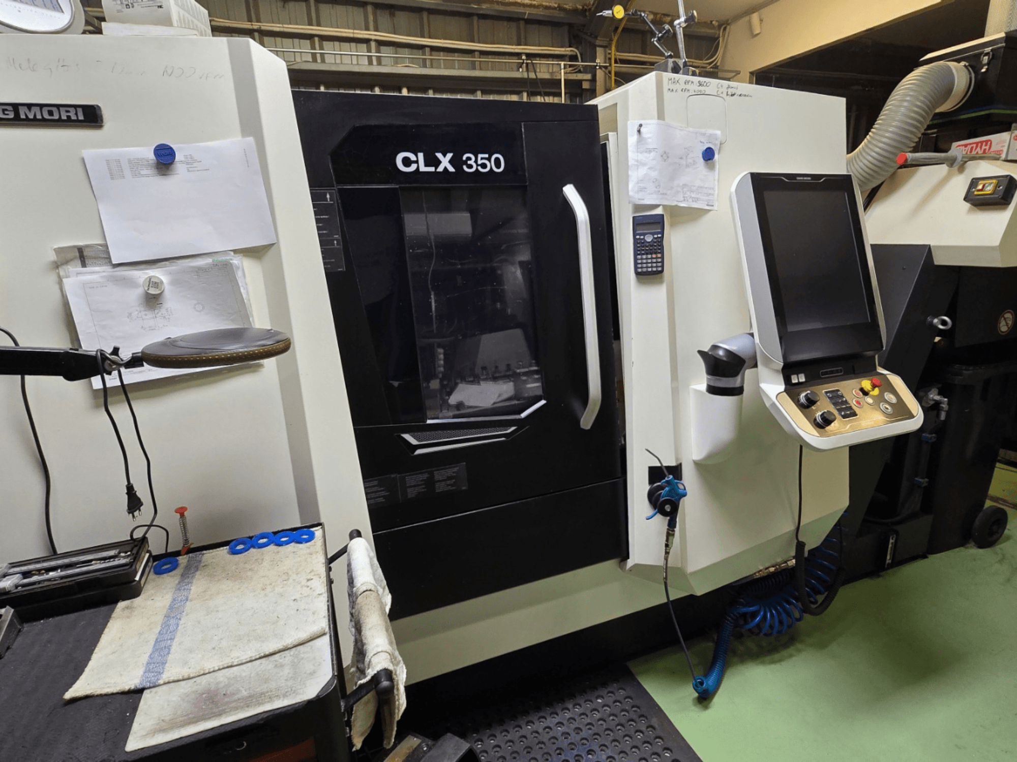 DMG MORI CLX 350 CNC-teenindusega treipink töökojas; esiplaanil on näha juhtpaneel, tööriistad ja tööruum.