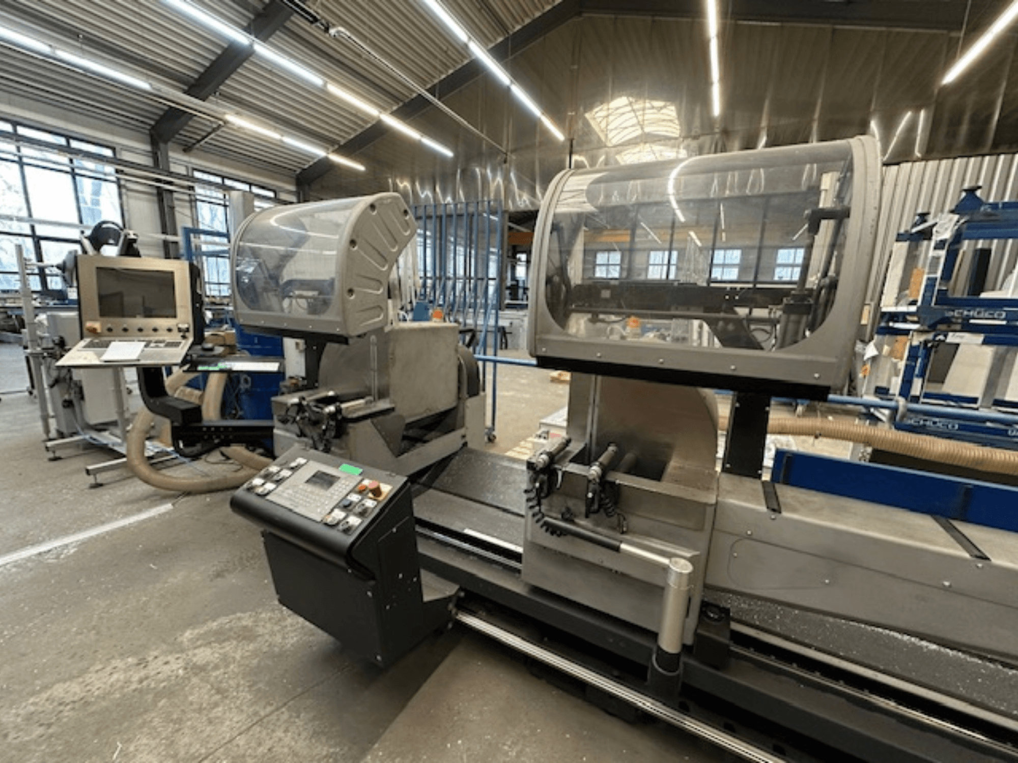 SCHÜCO PDG E CUT metallist ketassaag, esiplaanil, juhtpaneel, kaitsekatted ja lõikepind töökojas.