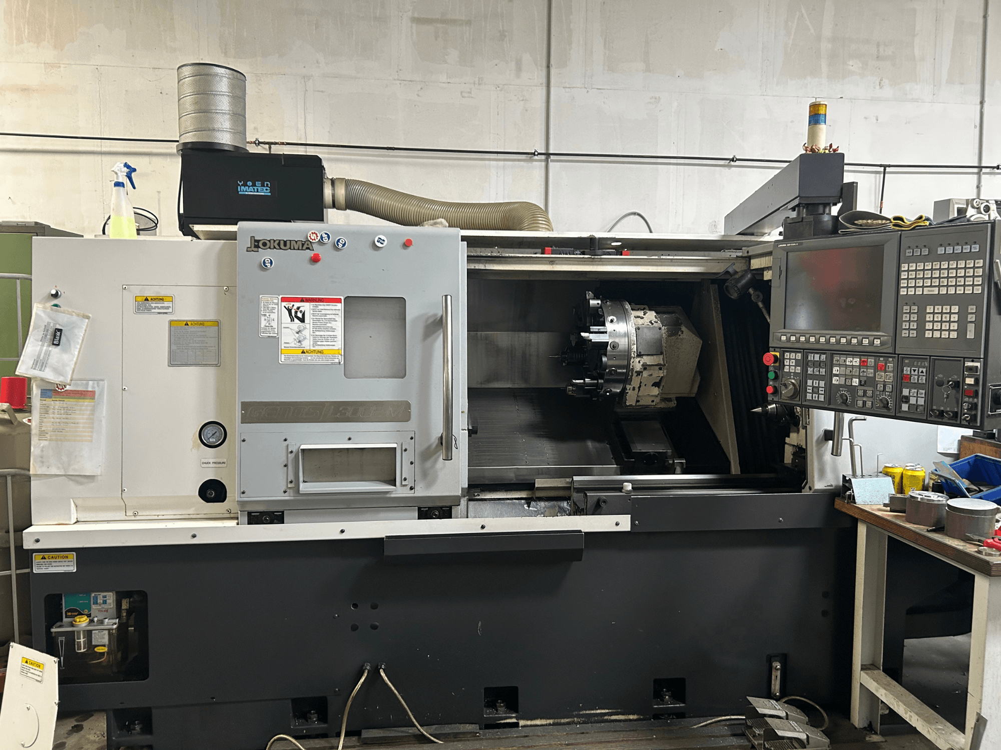 Okuma Genos L300E-M horisontaalse treipingi esivaade koos juhtpaneeli, nähtava spindli ja erinevate seadistustööriistadega.