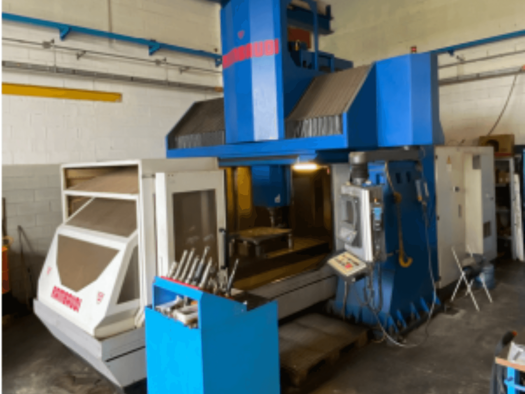 Vertikaalne töötlemiskeskus Rambaudi RF103, esivaade, kus on näidatud juhtimisseadmed, tööriistade hoidmine ja töötlemisala. Sinine ja valge välisilme.