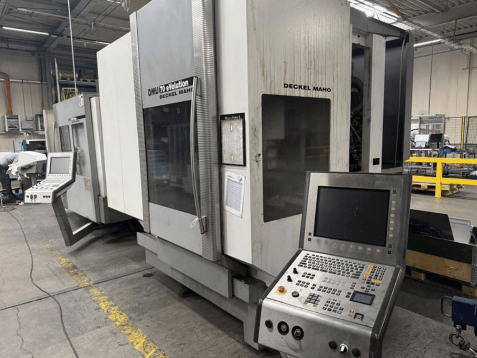 Esivaade Deckel Maho DMU 70 eVOLUTION CNC-tööpingist koos juhtpaneeliga, mis asub tootmisüksuses.
