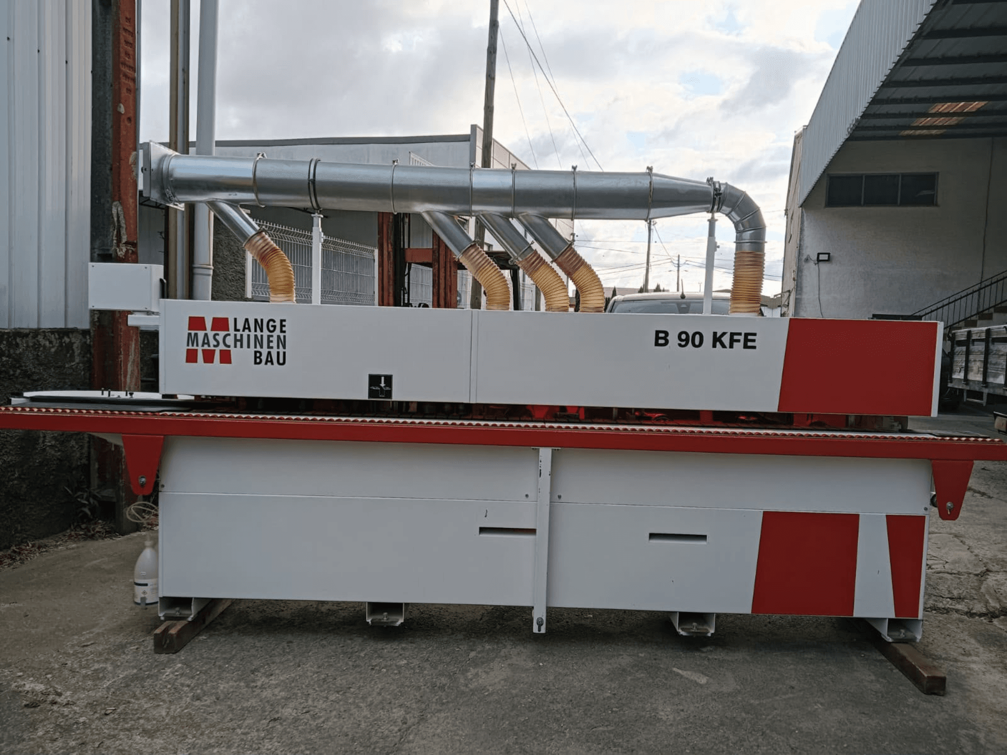 LANGE Maschinenbau B 90 KFE servakleebimismasin külgvaates, kahe väljalasketoruga ja punaste detailidega, paigutatud tööstuslikku töökeskkonda.