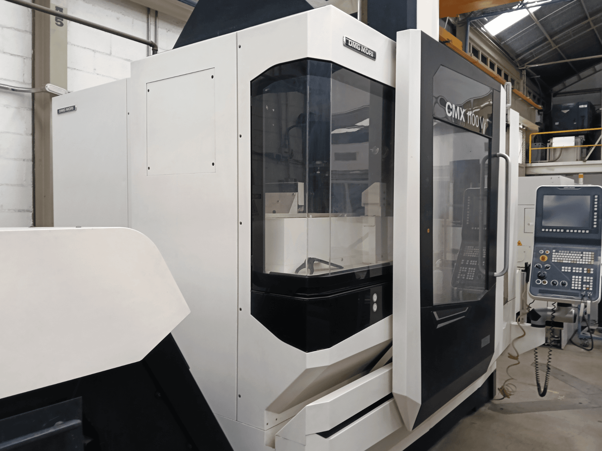 DMG MORI CMX 1100 V vertikaalne töötlemiskeskus, vaade eest, millel on näha juhtpaneel ja klaasist kaitsekate.