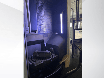 DMG MORI DMU 65 MonoBlock vertikaalne töötlemiskeskus, esivaade, millel on näha pöörlev laud töödeldava detailiga ja juhtpaneel.