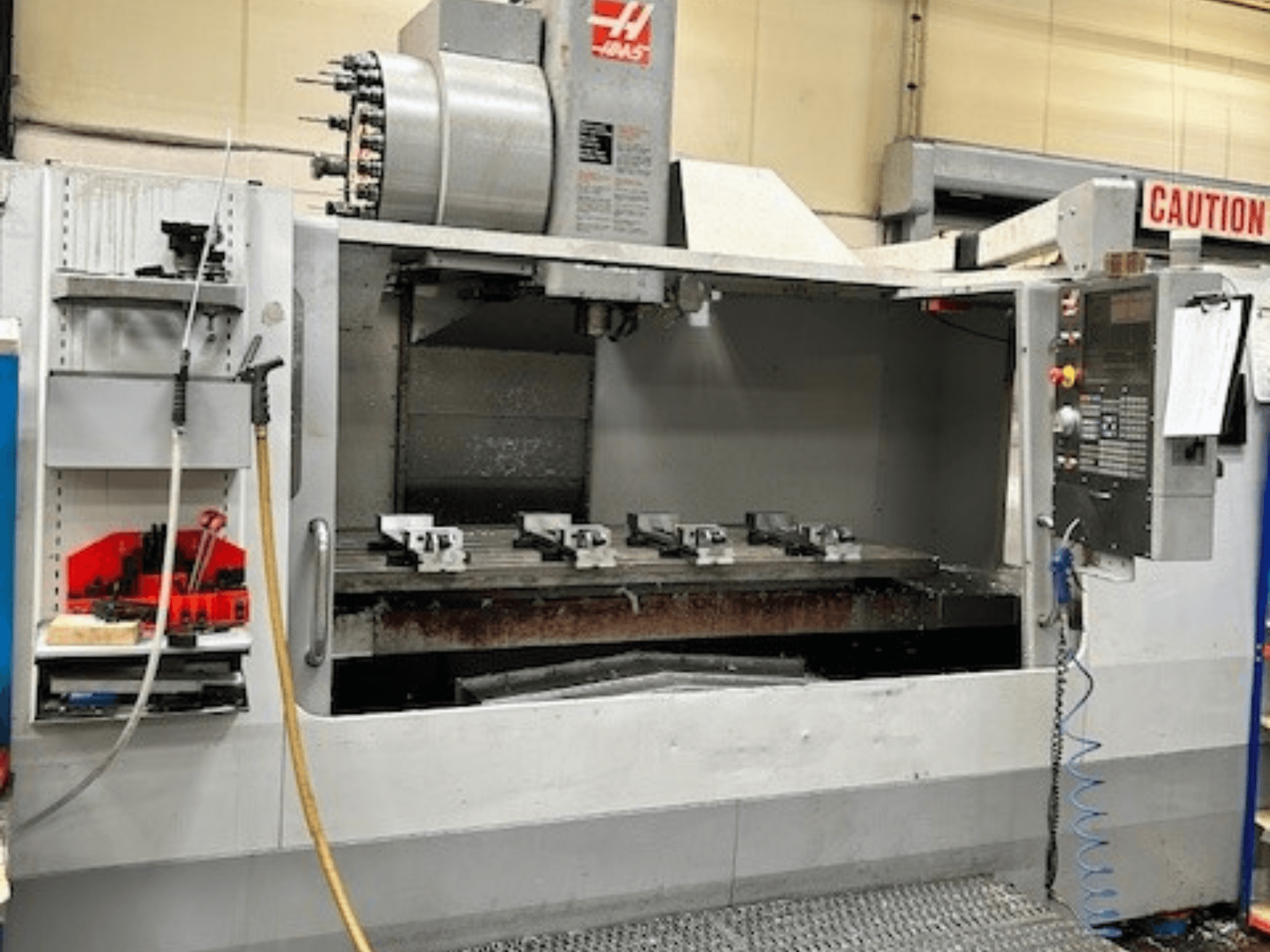 HAAS VF-9/40HE vertikaalne töötluskeskus, esiplaanil, tööriistahoidja ja lisatarvikud küljel nähtavad.