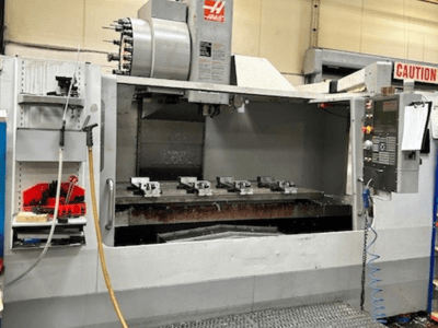 HAAS VF-9/40HE vertikaalne töötluskeskus, esiplaanil, tööriistahoidja ja lisatarvikud küljel nähtavad.