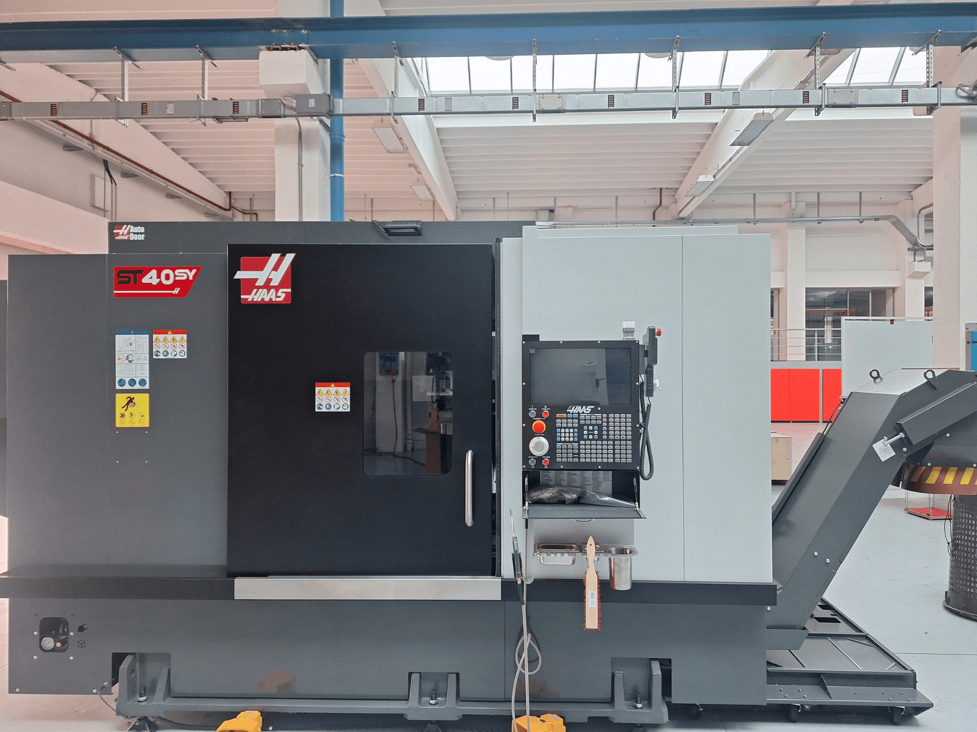 Haas ST-40SY horisontaalne treipink külgvaates, millel on juhtpaneel ja ohutusmärgised.