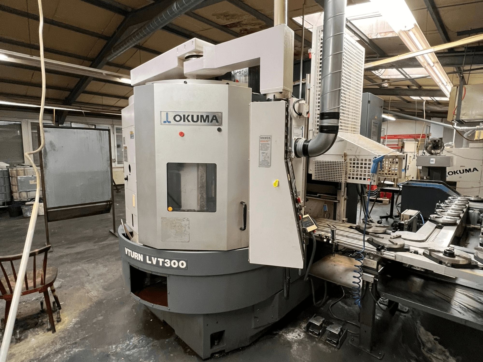 Okuma Vturn LVT300 CNC-teeninduspingi külgvaade tööstuslikus keskkonnas, kus näidatakse juhtpaneeli ja jahutusvedeliku süsteemi.