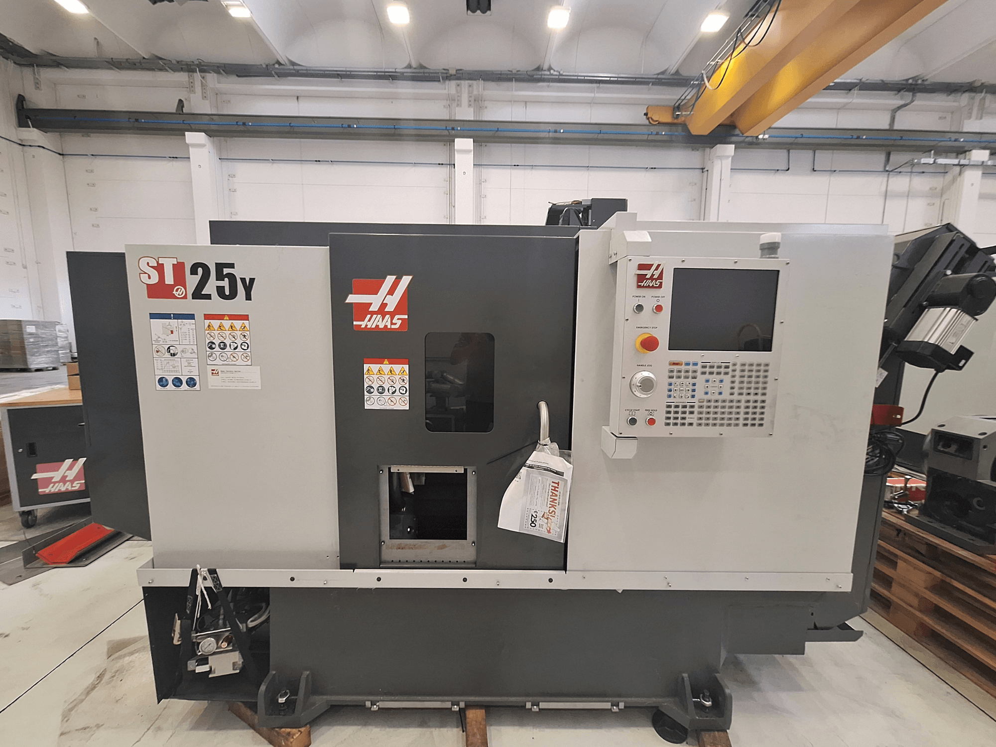 Haas ST-25Y horisontaalne treipink, vaade eest, millel on juhtpaneel ja ohutusmärgised. Ideaalne täppistöötluseks.