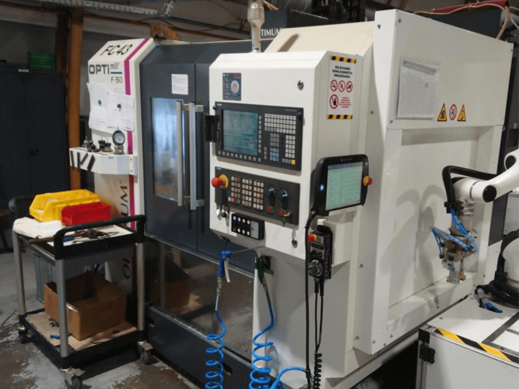 OPTIMUM F50 freespingi juhtpaneel koos voolikute, tööriistade ja robotkäega töökojas.