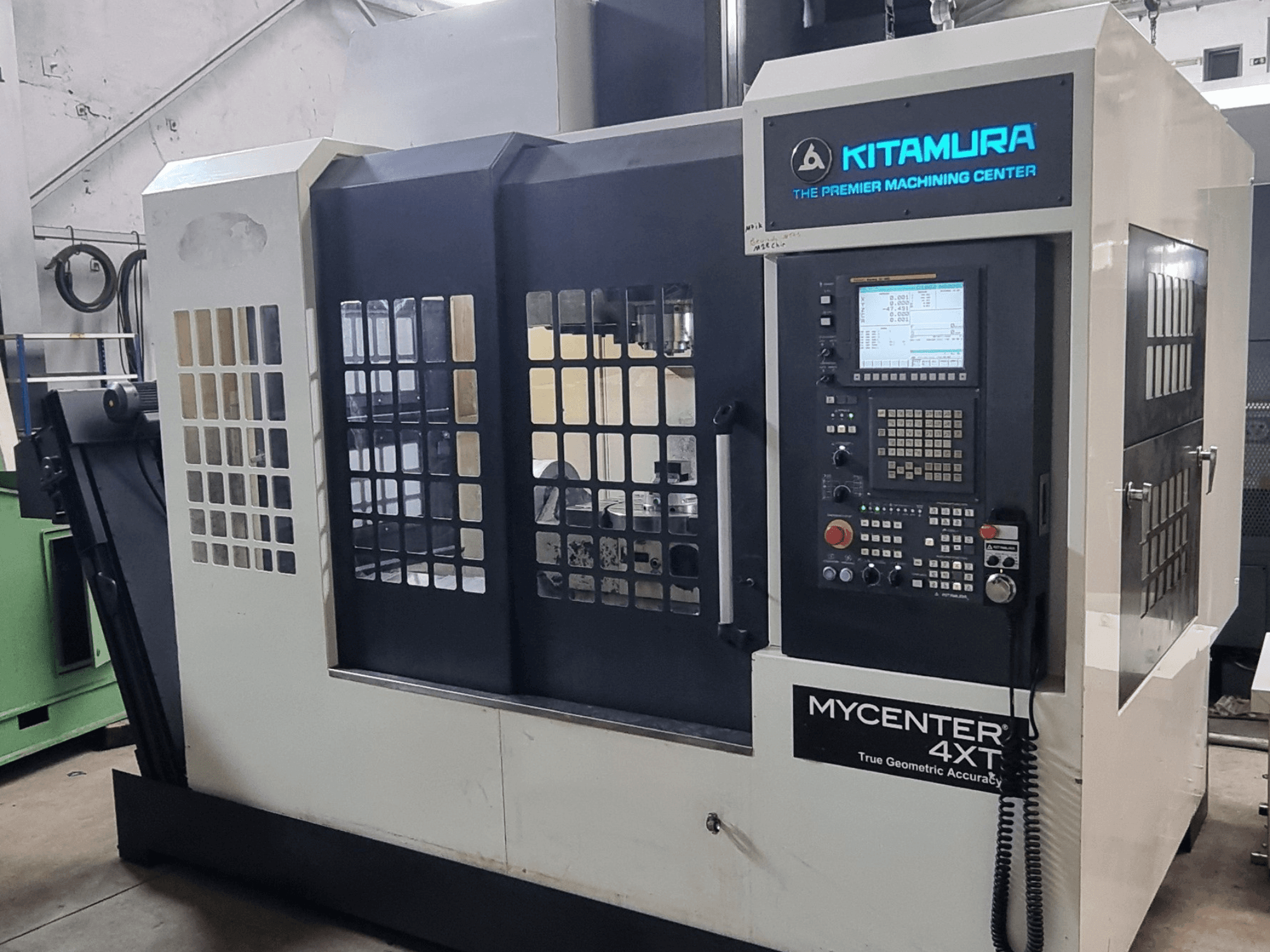 Alternatiivtekst: Kitamura MYCENTER 4XT vertikaalne töötlemiskeskus, vaade eest, millel on näha juhtpaneel ja masina üksikasjad töökoda keskkonnas.