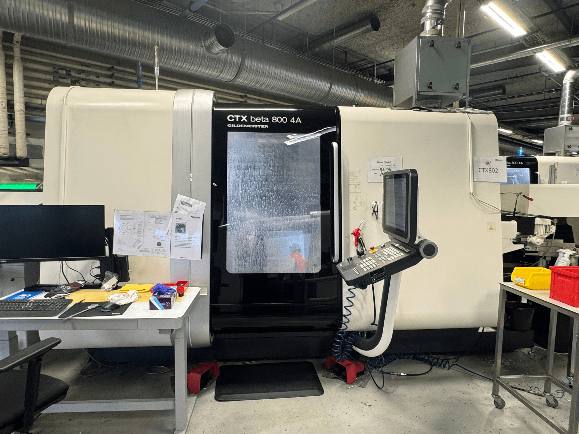 CTX beta 800 4A CNC-tööpink töökojas, külgvaates on näha juhtpaneel ja tööruum, mis on täis tööriistu ja dokumente.
