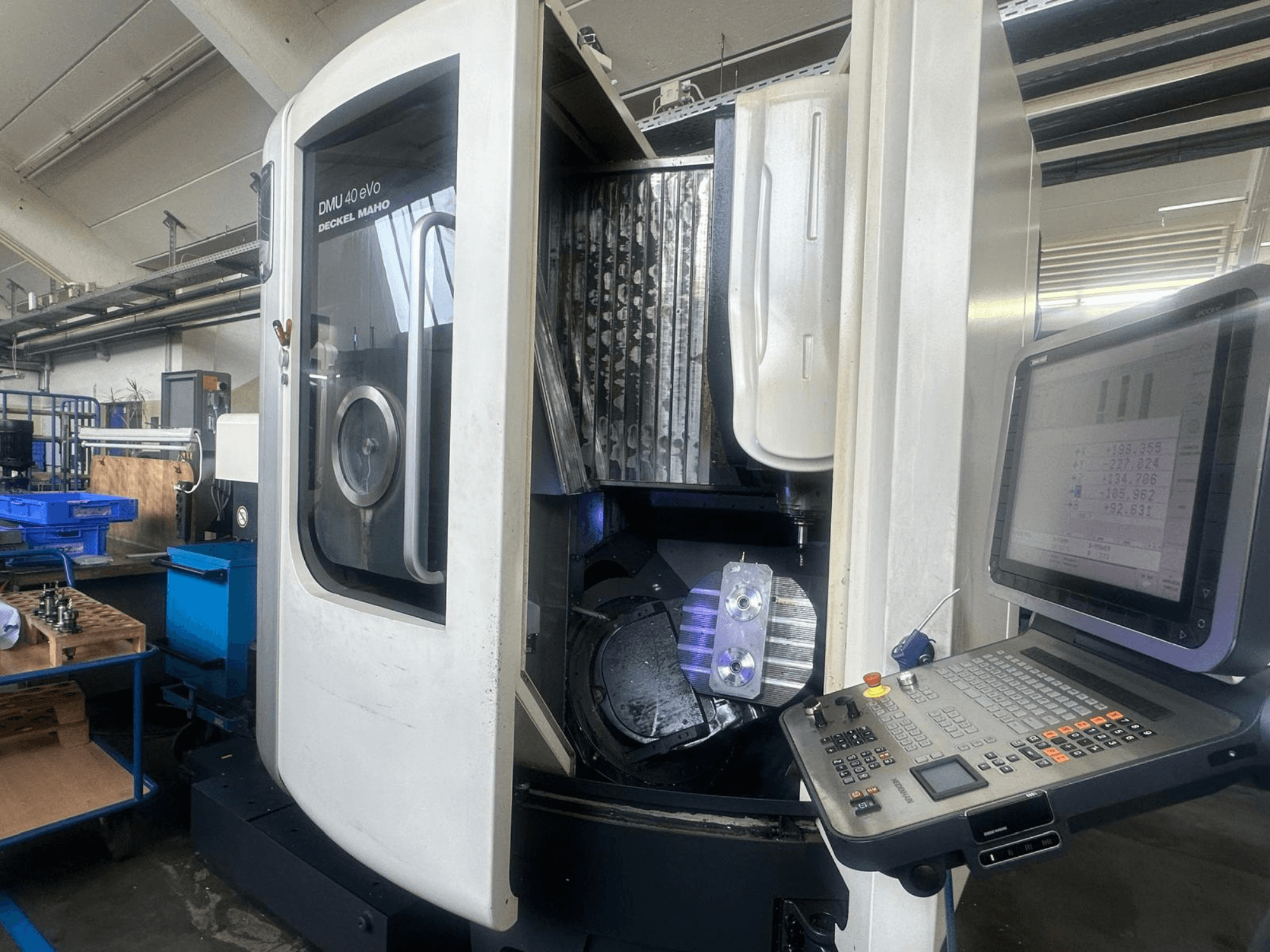 DMU 40 eVo freespink Deckel Maho töökojas, esivaade, kus on näidatud juhtpaneel ja metalltükk spindlis.