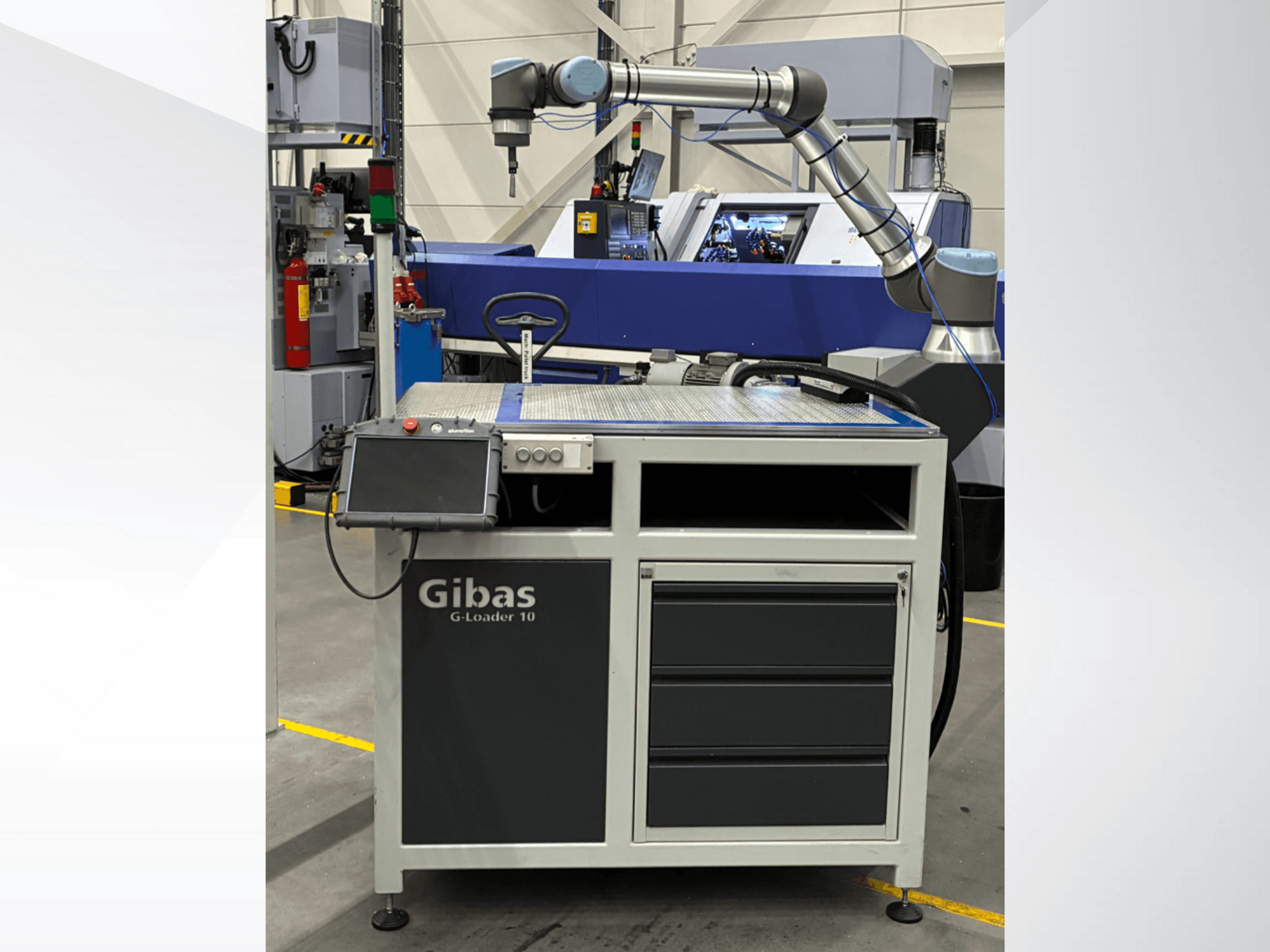 Gibas G-Loader 10 robotkäepidemega, esiplaanil; on varustatud puutetundliku juhtimisega ja sahtlisse paigutamisega tööstuslikus keskkonnas.