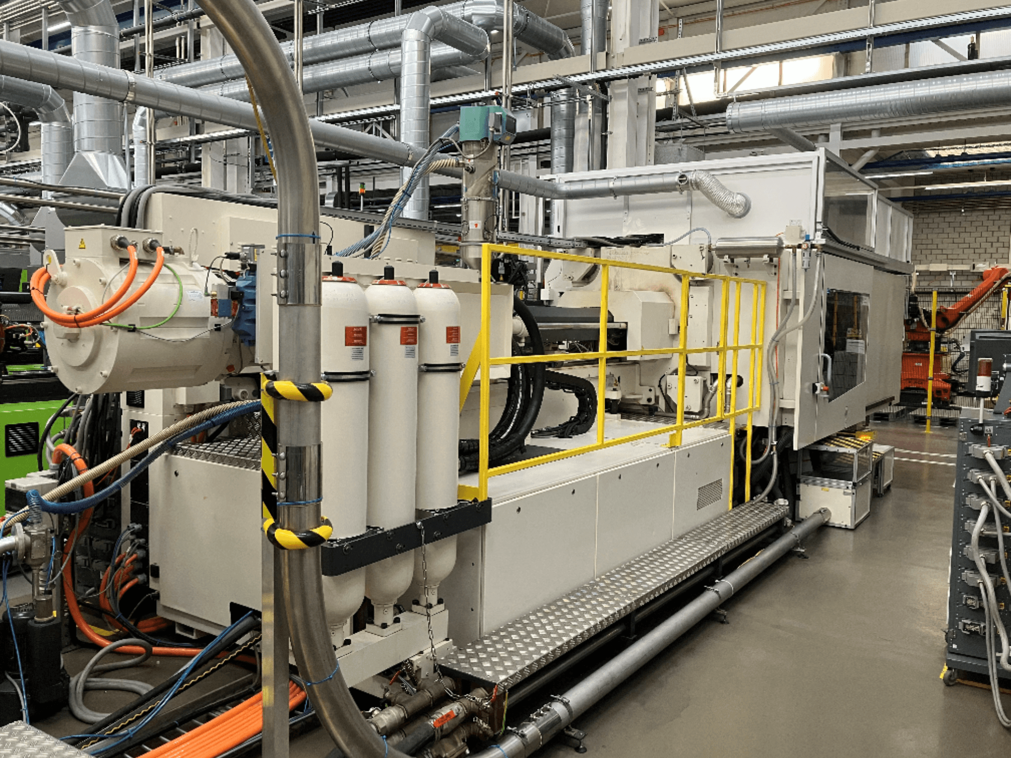 Tööstuslik masin valge ja halli korpuse, mitme vooliku ja filtritankidega; külgvaade, mis näitab töökorras seadistust.