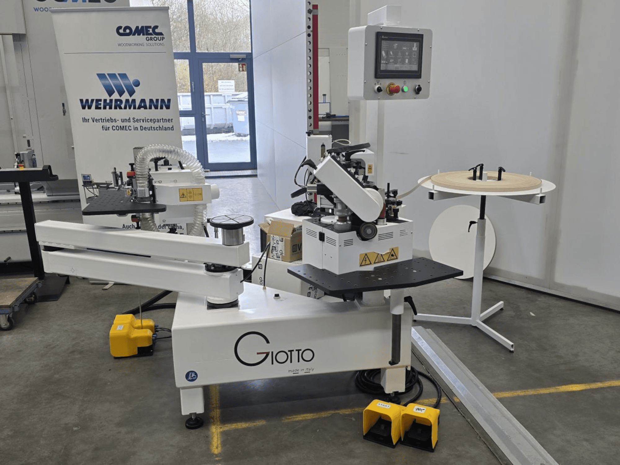 Giotto puidutöötlemismasin koos juhtpaneeliga, külgvaates, sisaldab jalapedaale ja pöörlevat tööpinda.