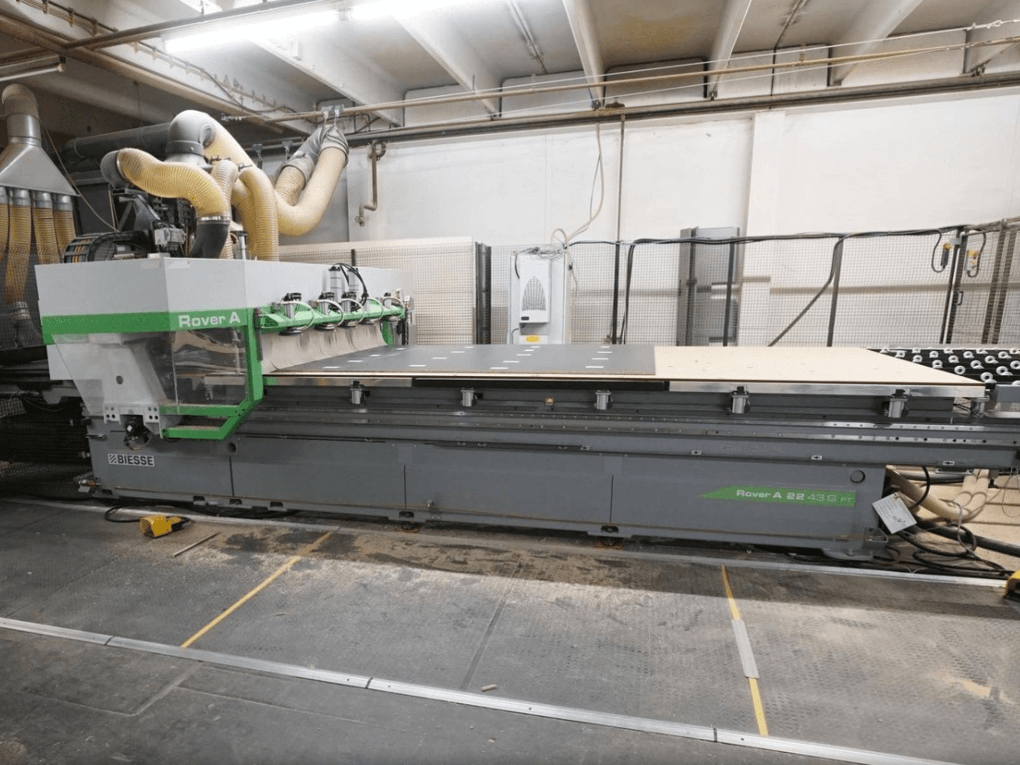CNC-puidutöötluskeskus BIESSE Rover A FT 2243, vaade eest, millel on suur tööpink ja tööriistade kinnitussüsteem.