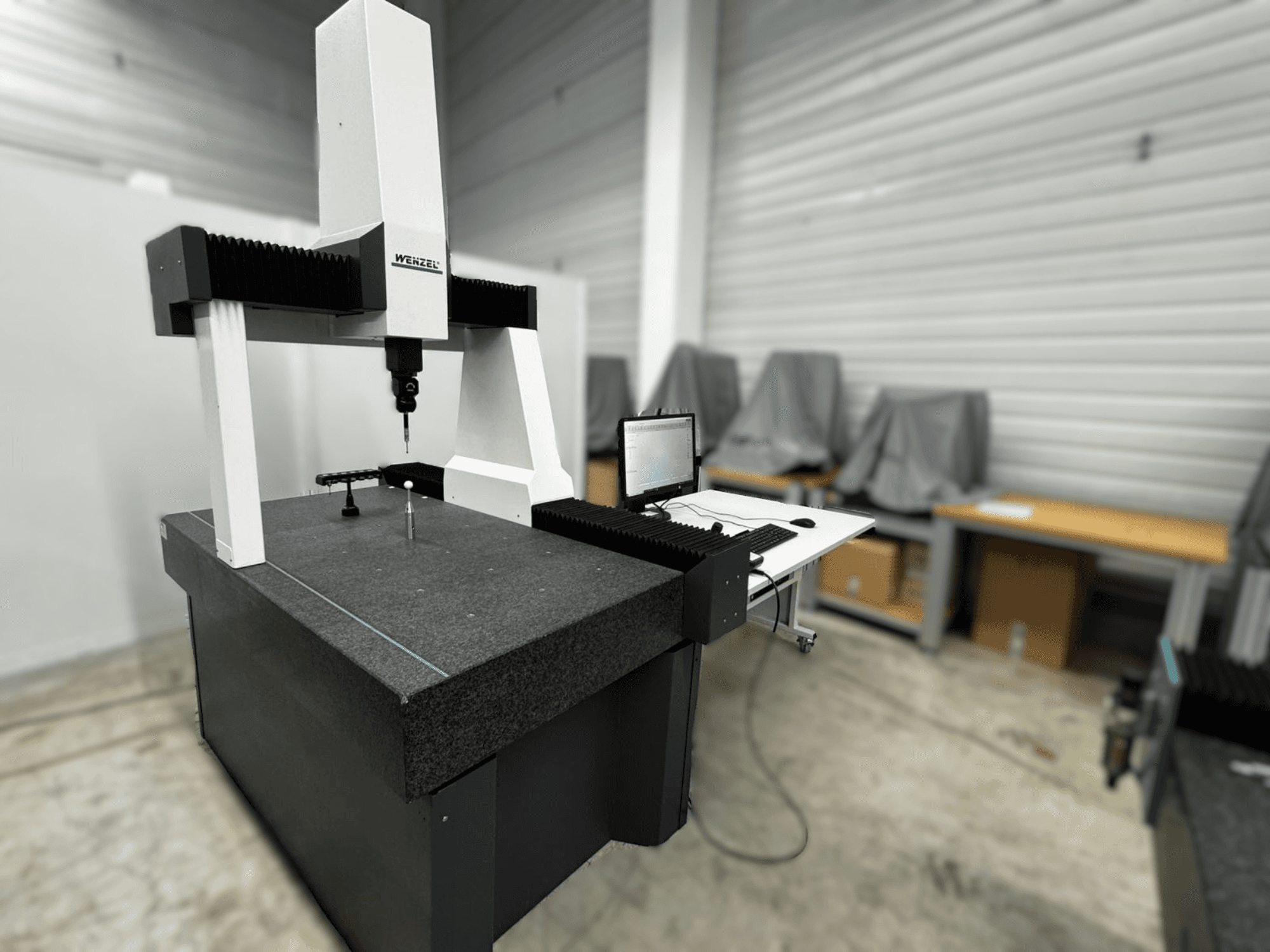 Wenzel LH 54 koordinaatmõõtemasin külgvaates, millel on sond ja arvutiliides halli aluse peal.