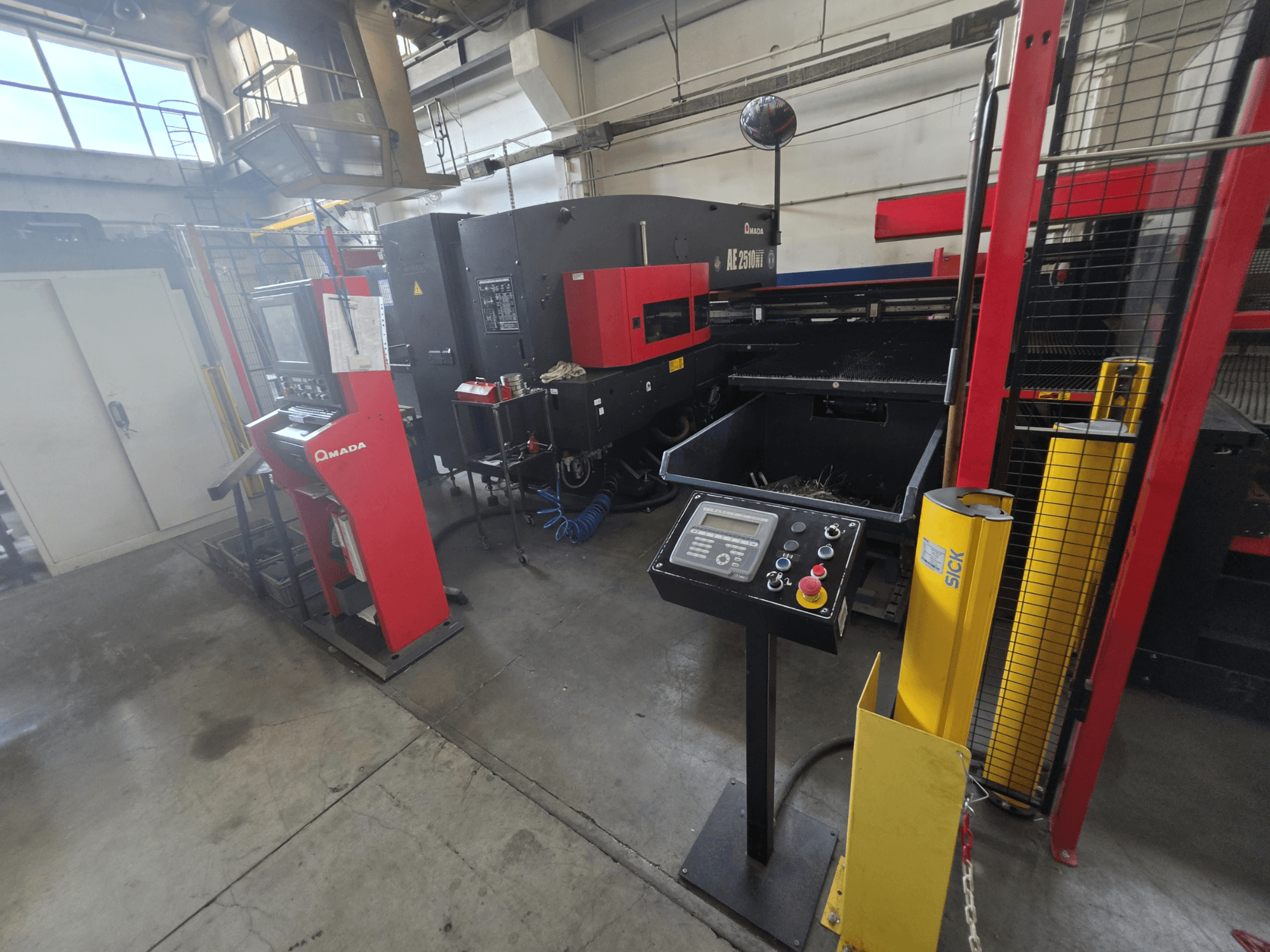 CNC-stantsimismasin AMADA AE-2510NT, vaade eest koos juhtpaneeli, ohutusseadmete ja ümbritseva tööstusliku keskkonnaga.