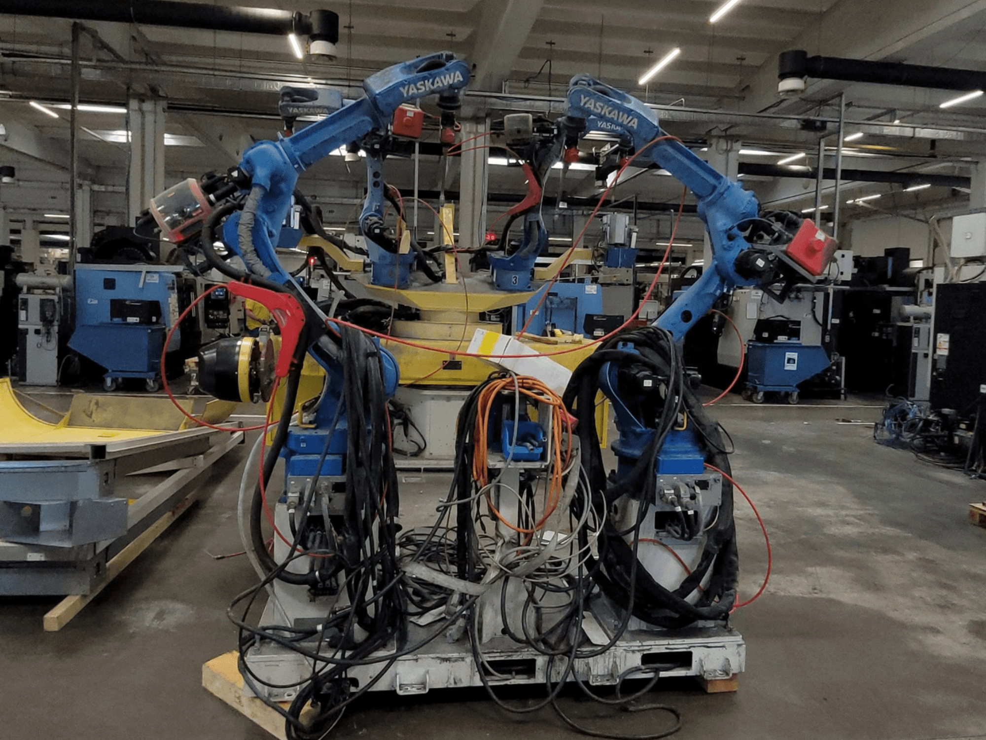 Yaskawa robotkeevitusrakendus RWC L1_OS 15330, vaade eest, millel on kaks sinist robotit koos pikkade kaablite ja keevitusriistadega.