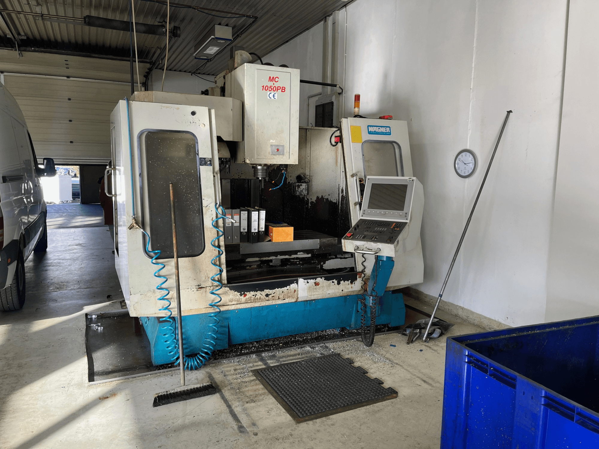 WAGNER MC 1050PB CNC-tööpink töökojas, esivaade, juhtpaneel ja tööala; nähtav on sinine õhuvoolik ja puhastusvahendid.