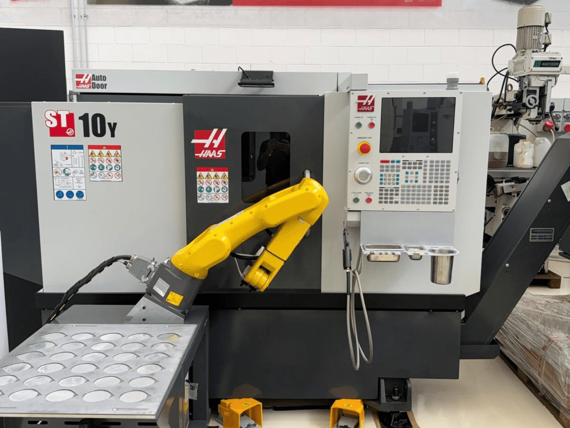 Haas ST-10Y horisontaalne treipink vaadatuna eestpoolt, millel on robotkäsi ja juhtpaneel koos tööriistahoidjate alustega.