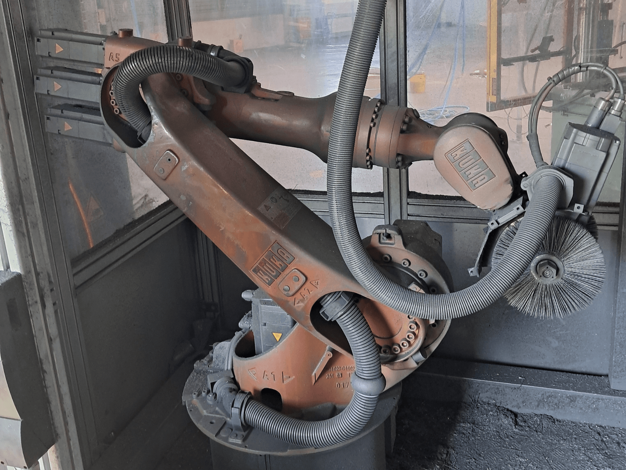 KUKA KR 16-2 robotkäsi külgvaates, millel on näha kaablid, harjad ja mehaanilised liigendid töökeskkonnas.