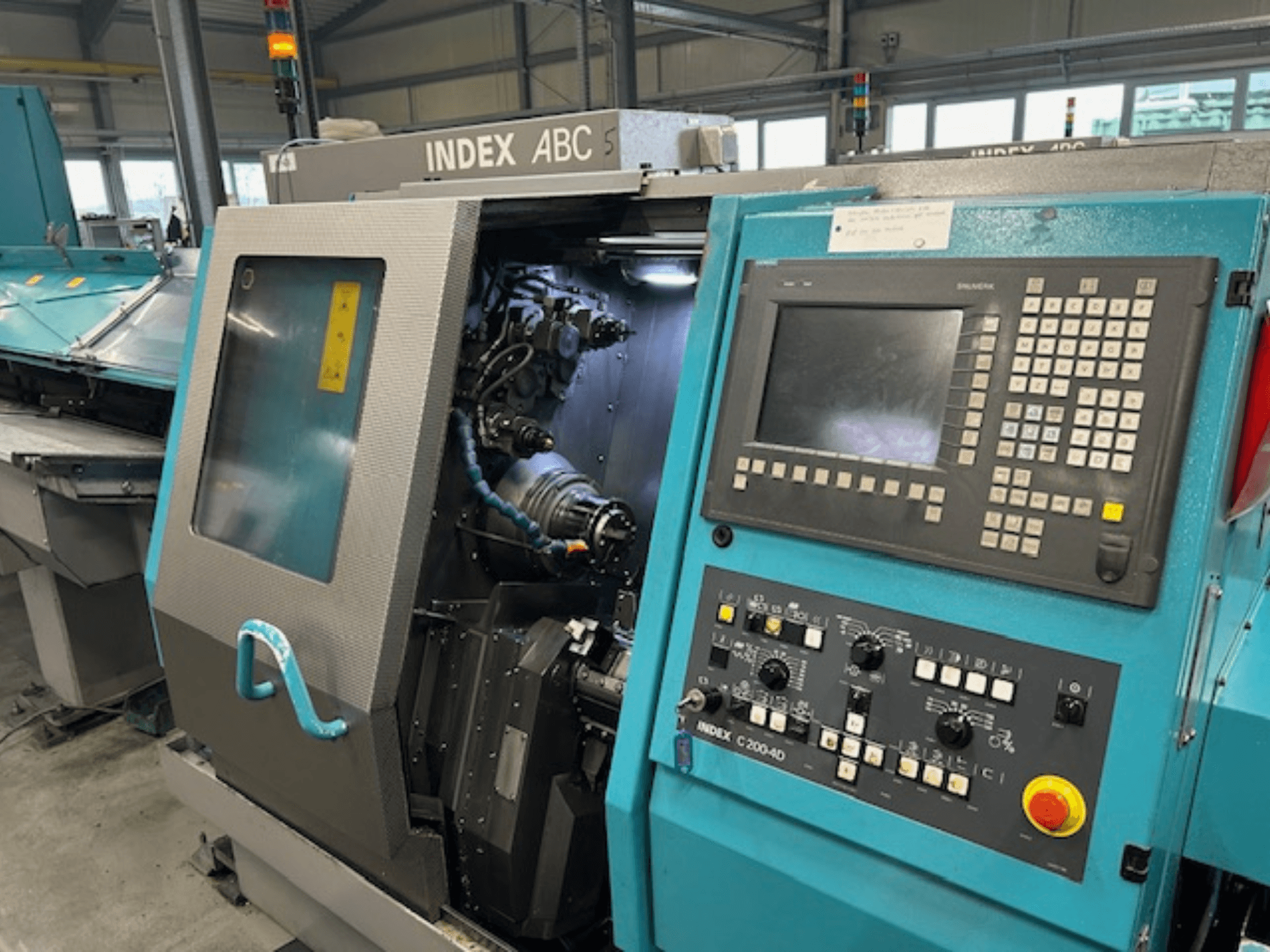 INDEX C200-AD CNC-tööpinki esivaade koos juhtpaneeli, nähtavate sisemiste komponentide ja turvaelementidega.