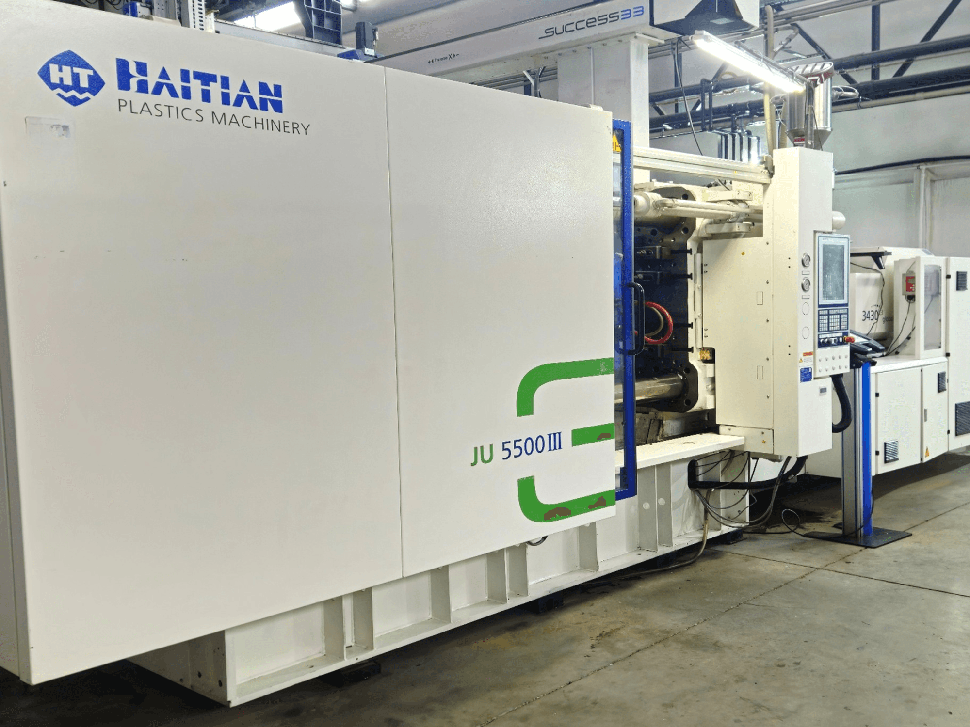 Haitian JU 5500III plastmasinad tehases, esiplaanil on juhtpaneel ja tootmisala.