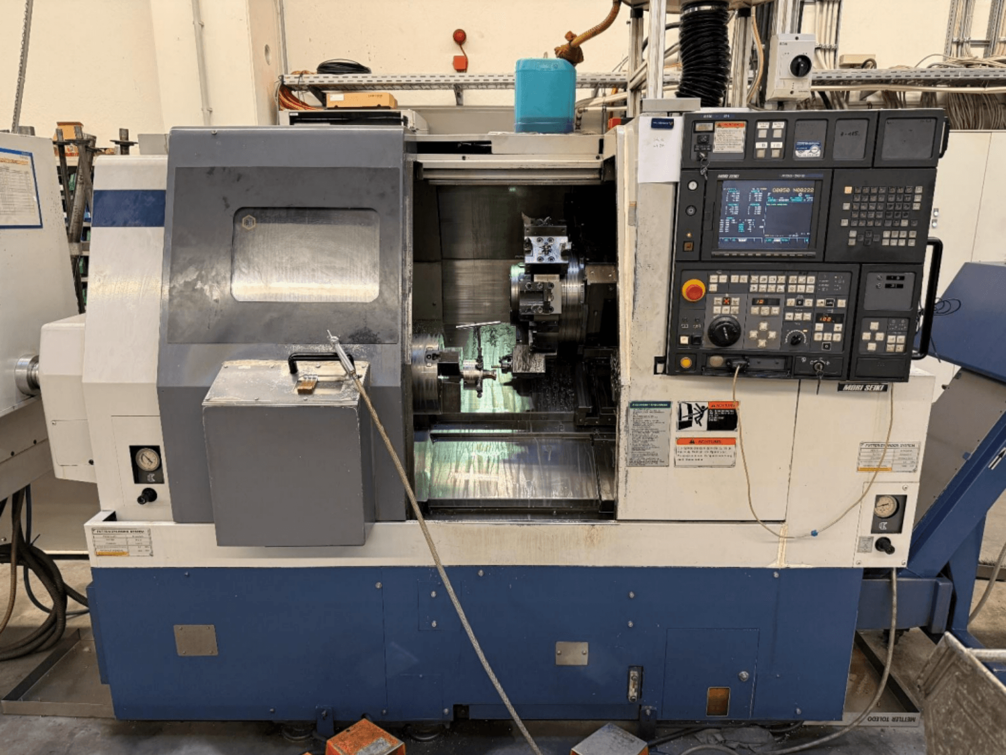 MORI SEIKI SL-250ASMC treimis- ja freesimiskeskus, esivaade, millel on näha juhtpaneel ja töödeldava detaili kinnitusklambri töö.