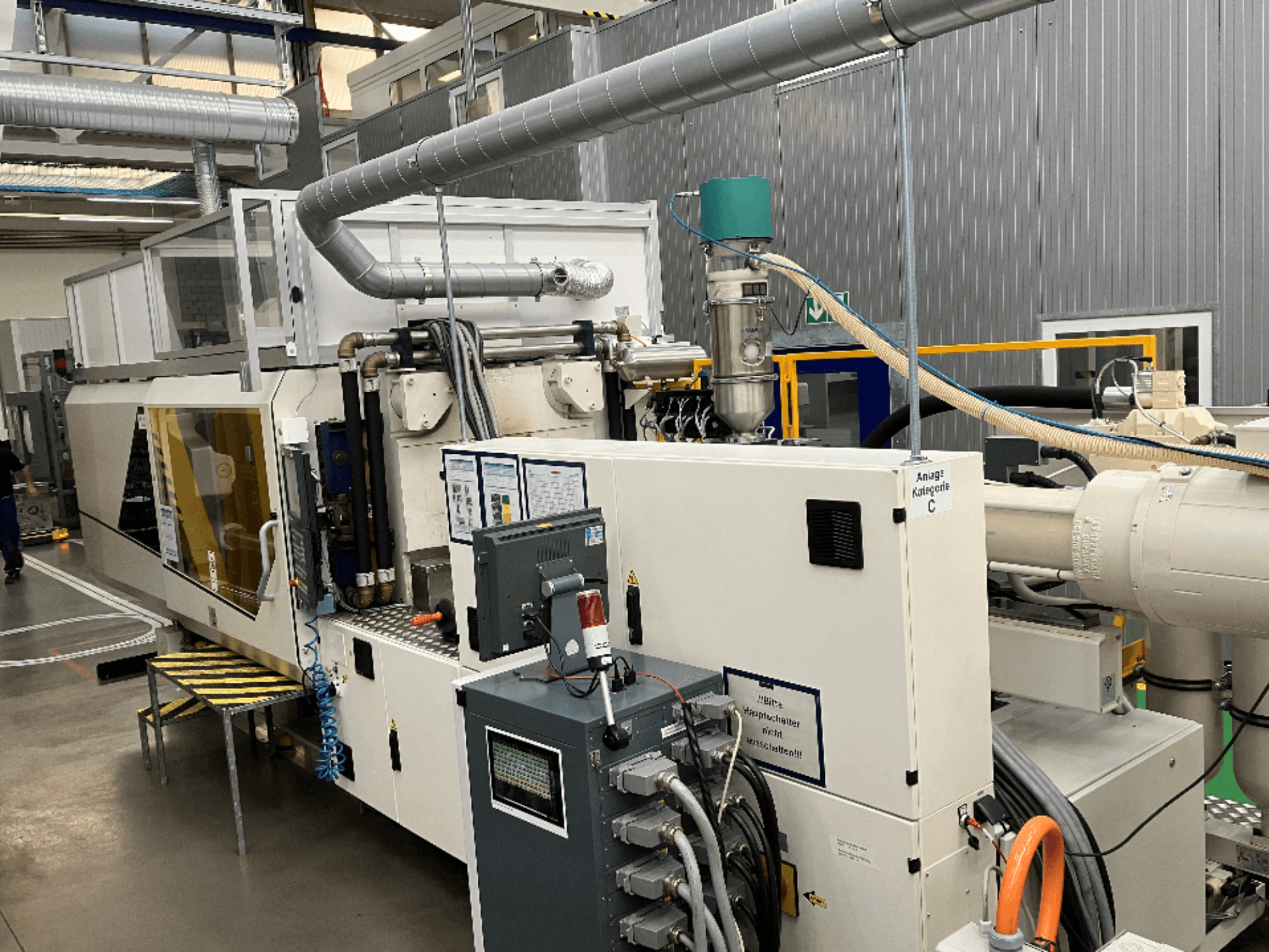 Süstevalu masin, esivaade, millel on kaubamärgi silt, juhtpaneel ja nähtavad voolikud tehases.