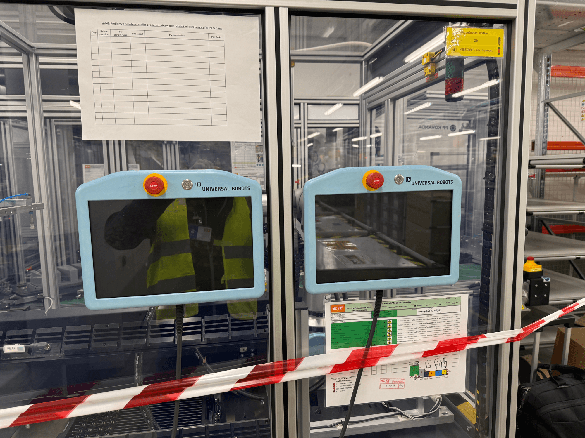 Juhtpaneel Universal Robots UR5 e robotkäe jaoks, millel on kaks monitori, hädaseiskamisnupud ja ohutusjuhised.