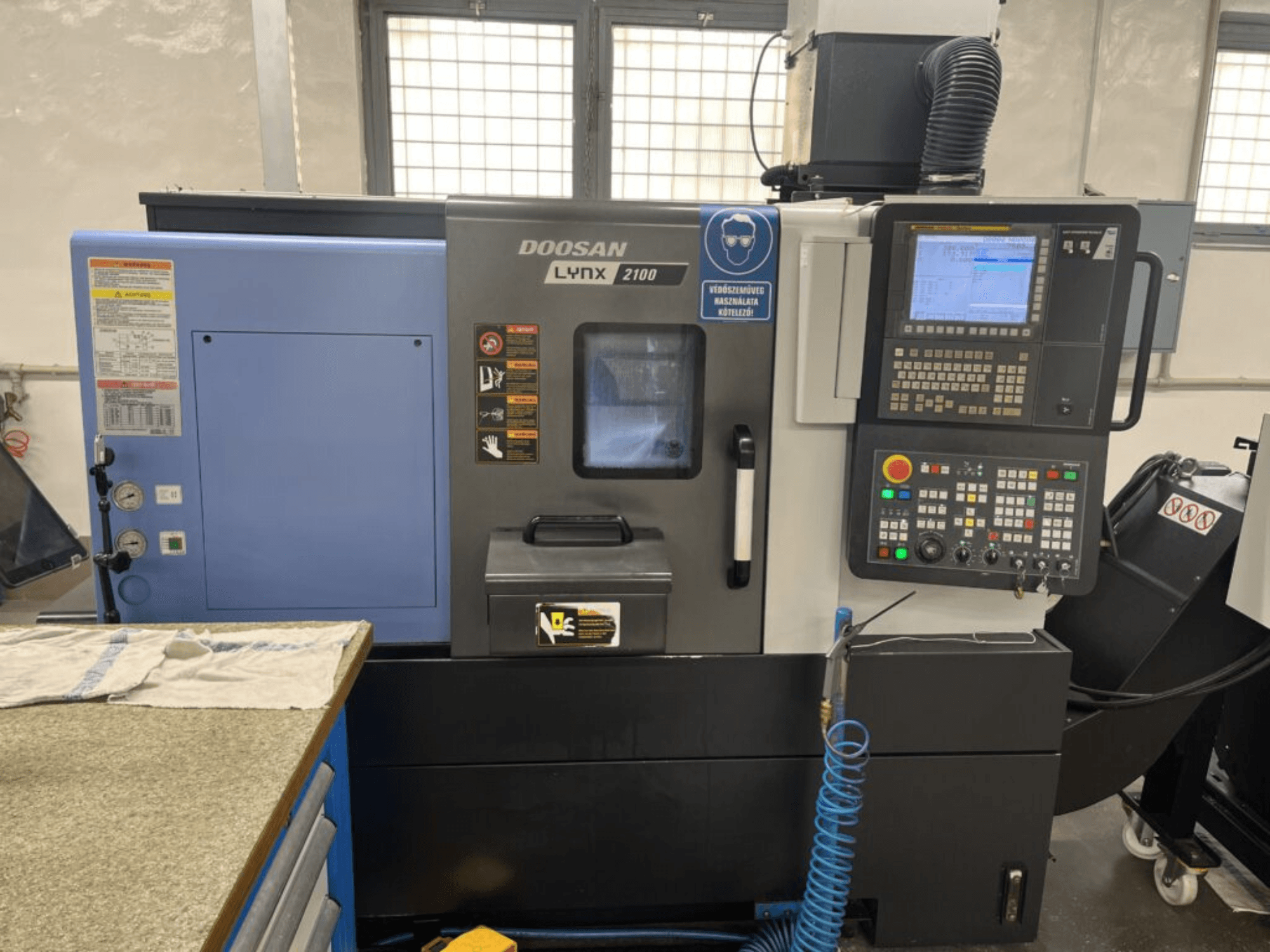 DOOSAN Lynx 2100A horisontaalne treipink, esiplaanil on juhtpaneel, operaatoriliides ja masina funktsioonid.
