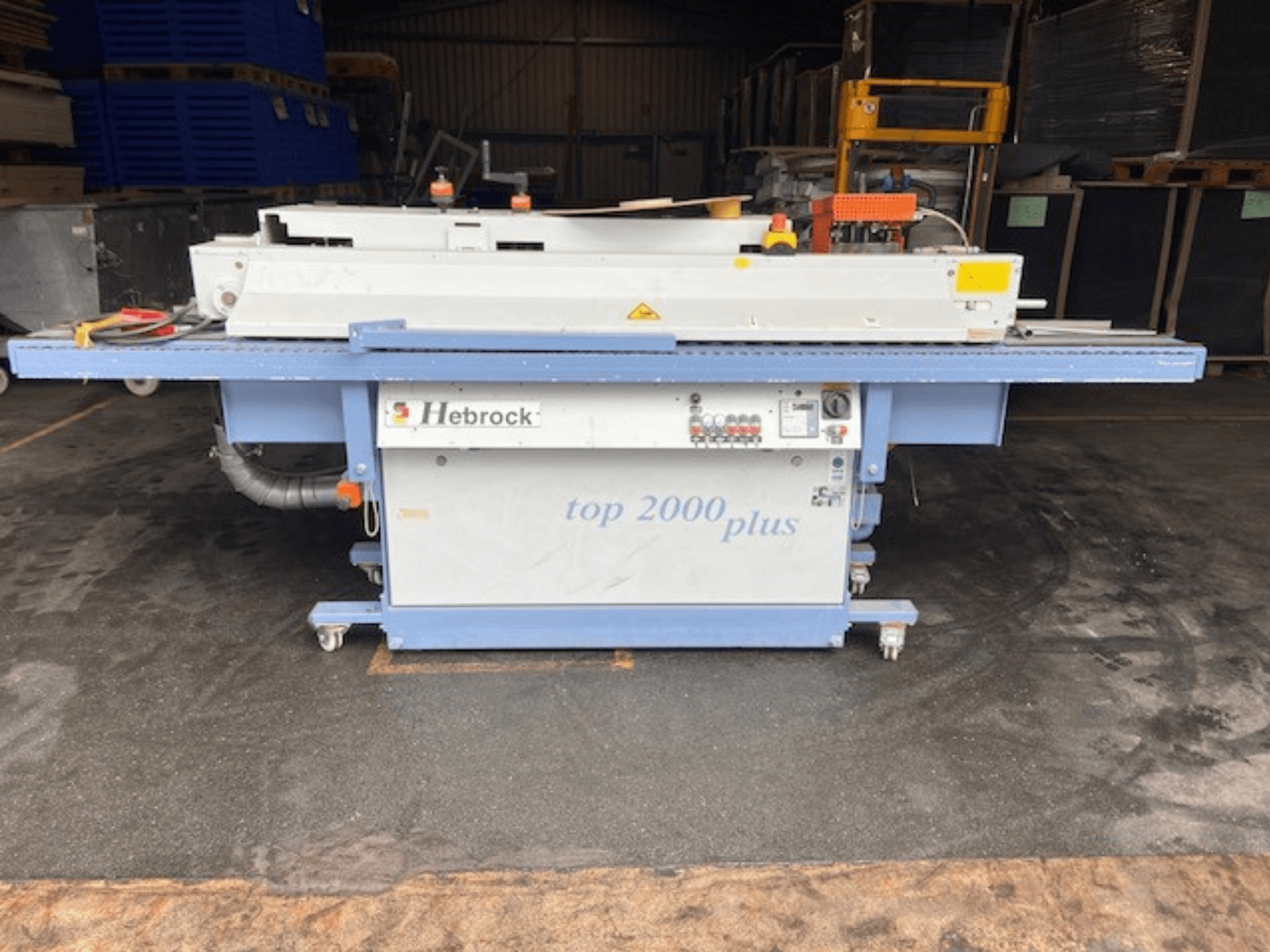 Hebrock Top 2000 Plus, esivaade; tööstuslik elektriline masin juhtpaneeliga, liikuvuse tagamiseks rattad ja ohutussildid nähtavad.