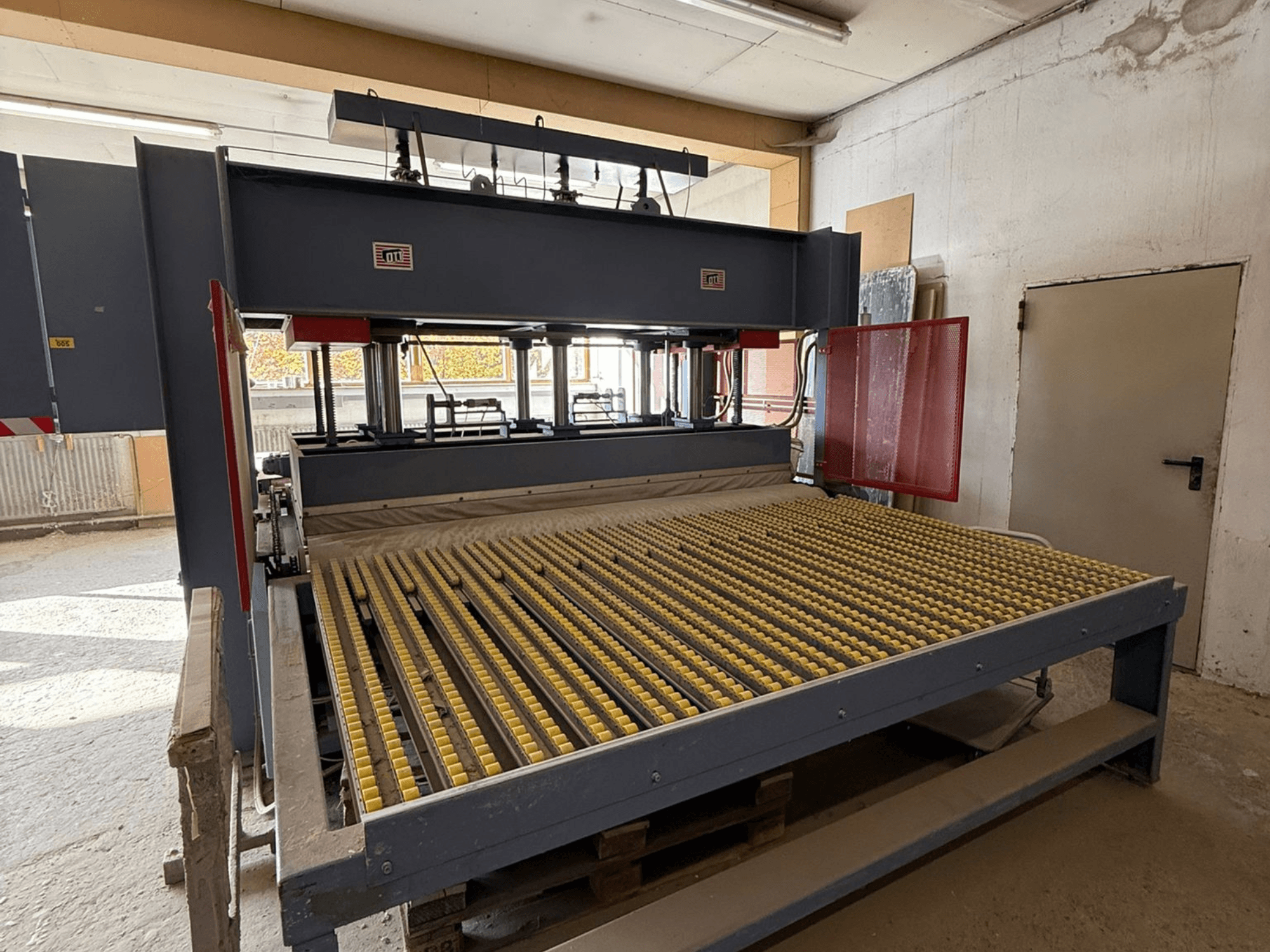 Kollaste rullidega tööstuslik masin, esiplaanil, kaubamärgi logo nähtav, mida kasutatakse materjalide töötlemiseks töökojas.