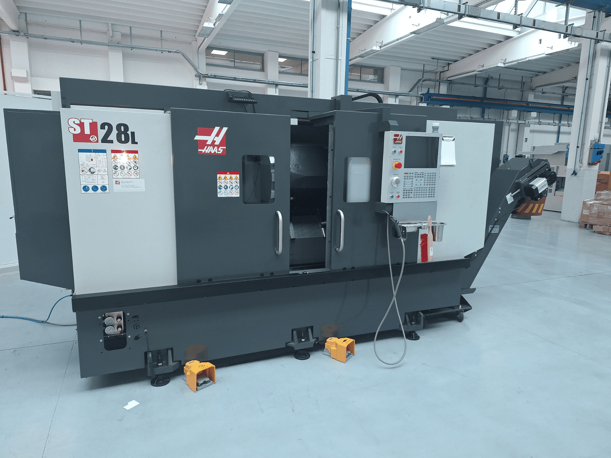 Haas ST-28L horisontaalse treipingi külgvaade, millel on näha juhtpaneel, juhtnupud ja ohutusmärgised.