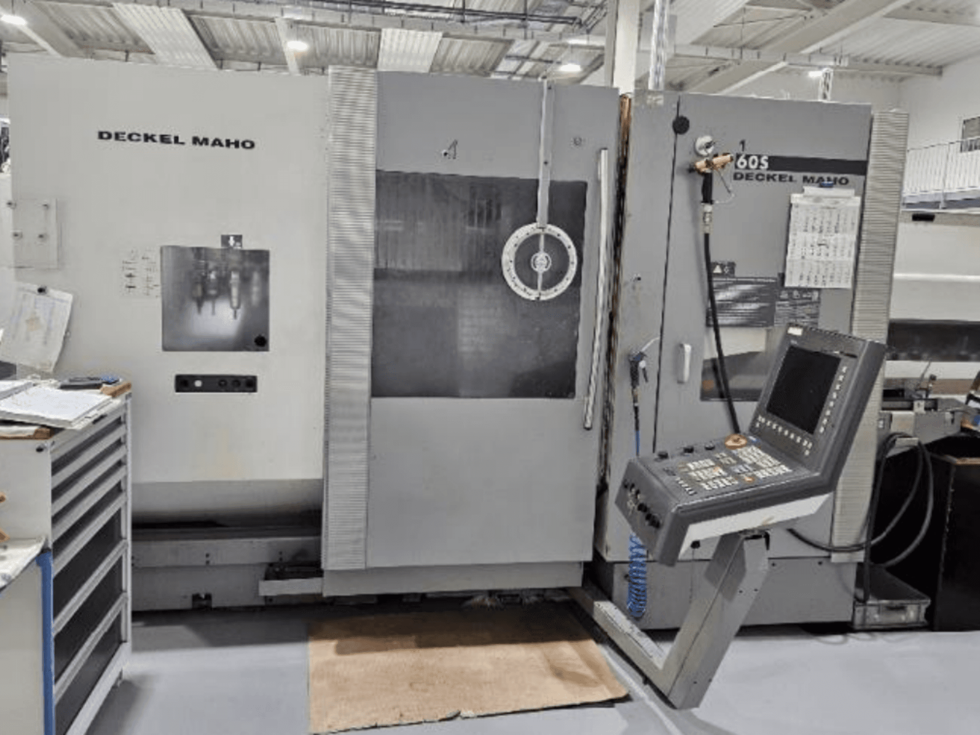 DECKEL MAHO 60S CNC-tööpinkide esikülg koos juhtpaneeliga, tööriistad nähtavad, töökojas.